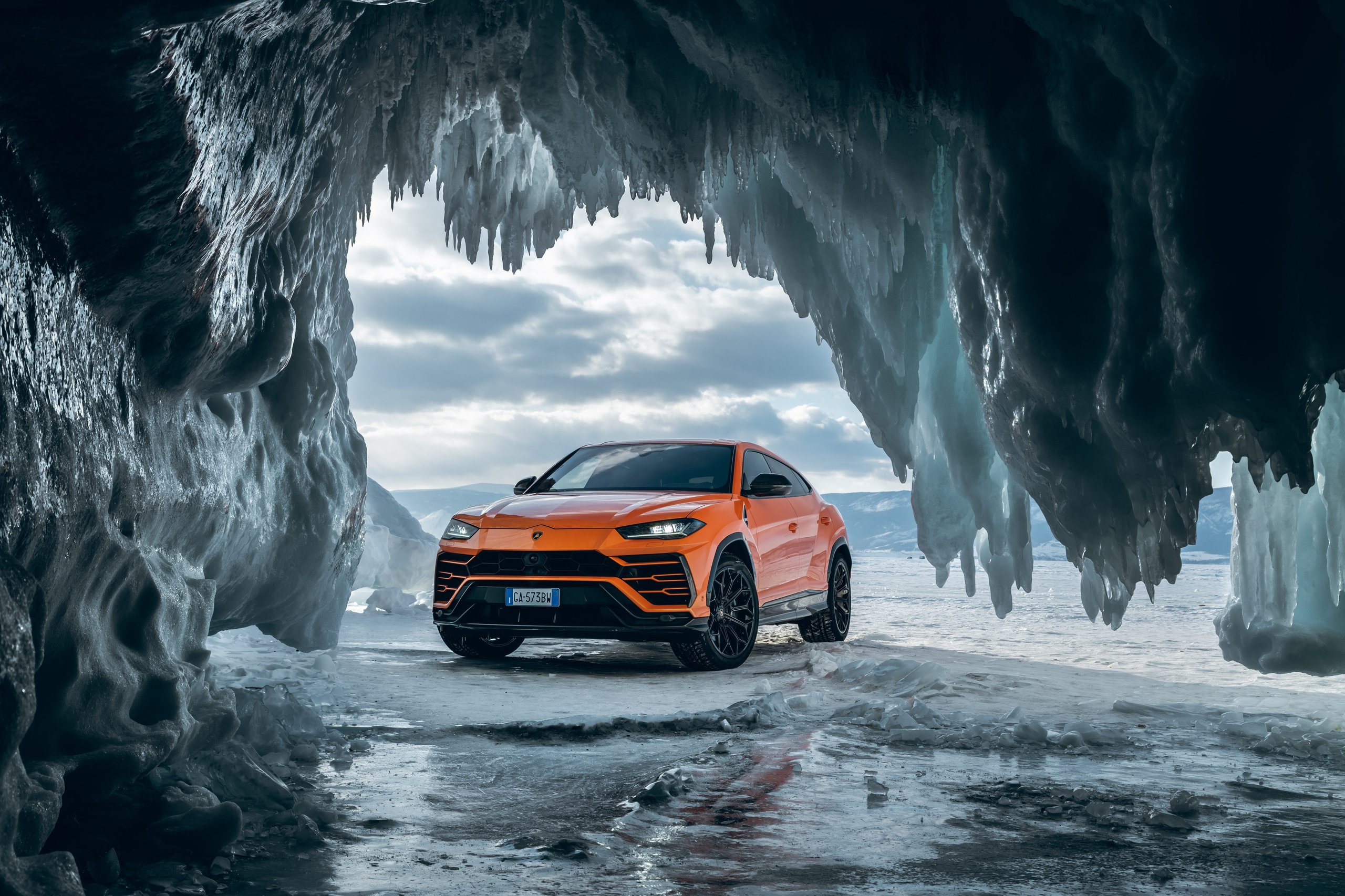 20,000 Urus Units In Four Years: How Lamborghini'S Bestseller Doubled The Entire Company 11 Orange lamborghini urus parked inside a dramatic ice cave, showcasing extreme-environment capability
