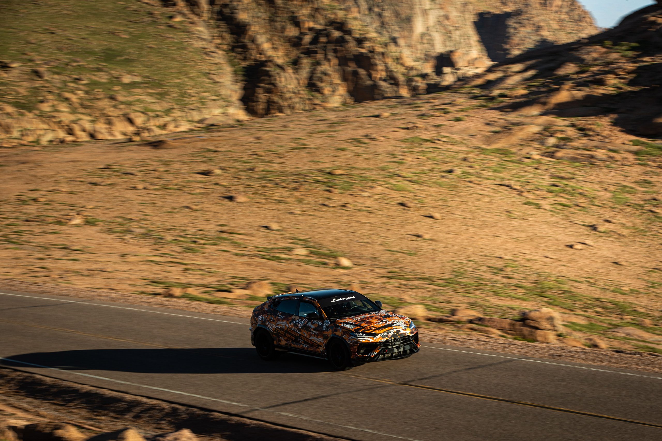 A Camouflaged Urus Just Demolished The Pikes Peak Suv Record By 17 Seconds 3 Camouflaged lamborghini urus performante driving on a winding mountain road with rocky terrain at pikes peak