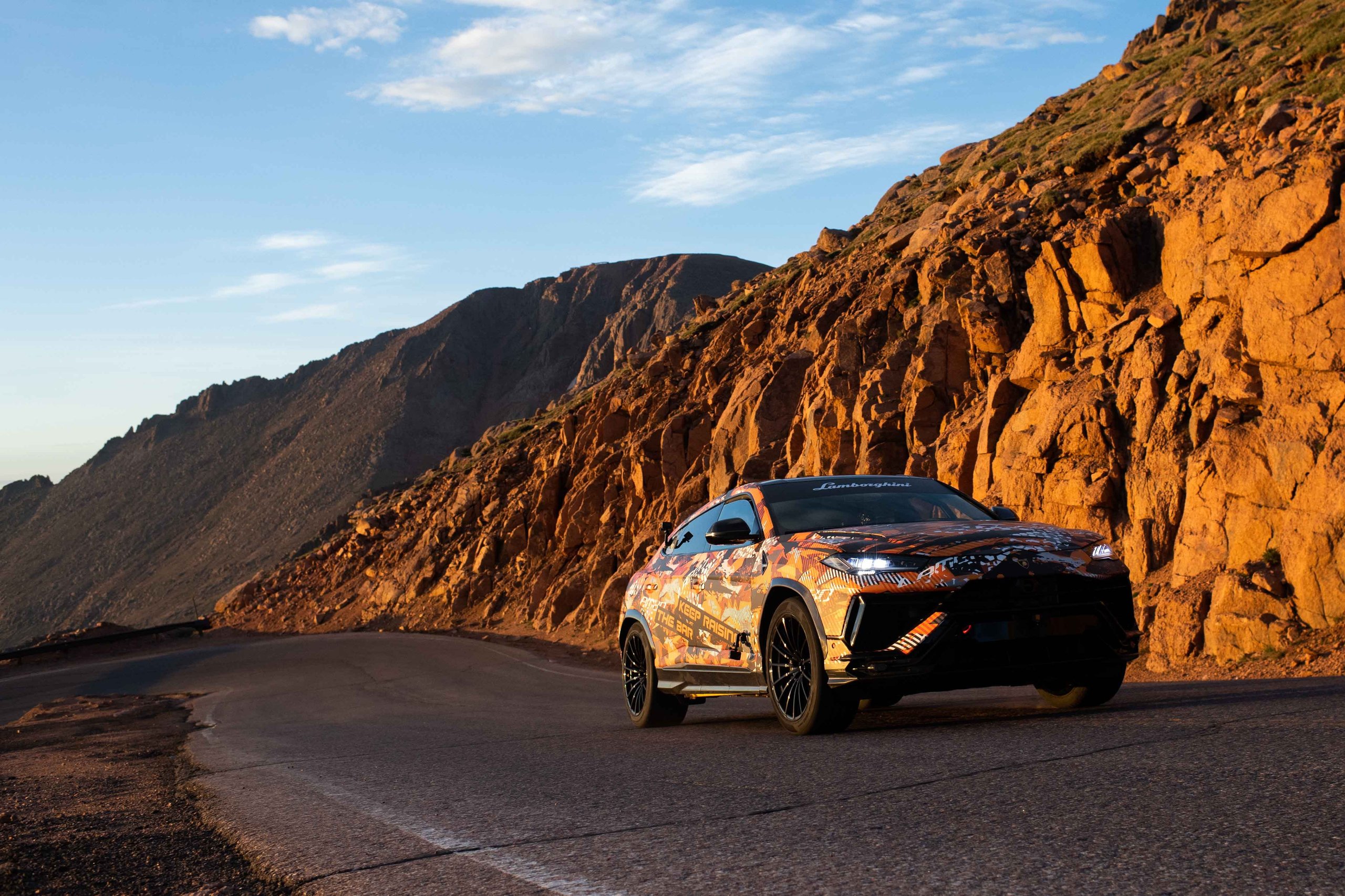 A Camouflaged Urus Just Demolished The Pikes Peak Suv Record By 17 Seconds 5 Camouflaged lamborghini urus navigating a winding mountain road with rugged rock formations at pikes peak