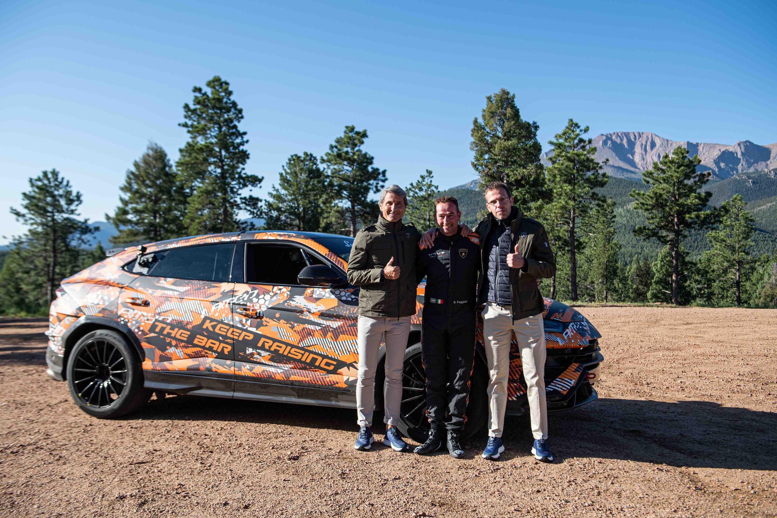 A Camouflaged Urus Just Demolished The Pikes Peak Suv Record By 17 Seconds 9 Three team members including the driver standing in front of the camouflaged lamborghini urus performante with 'keep raising the bar' visible on the wrap