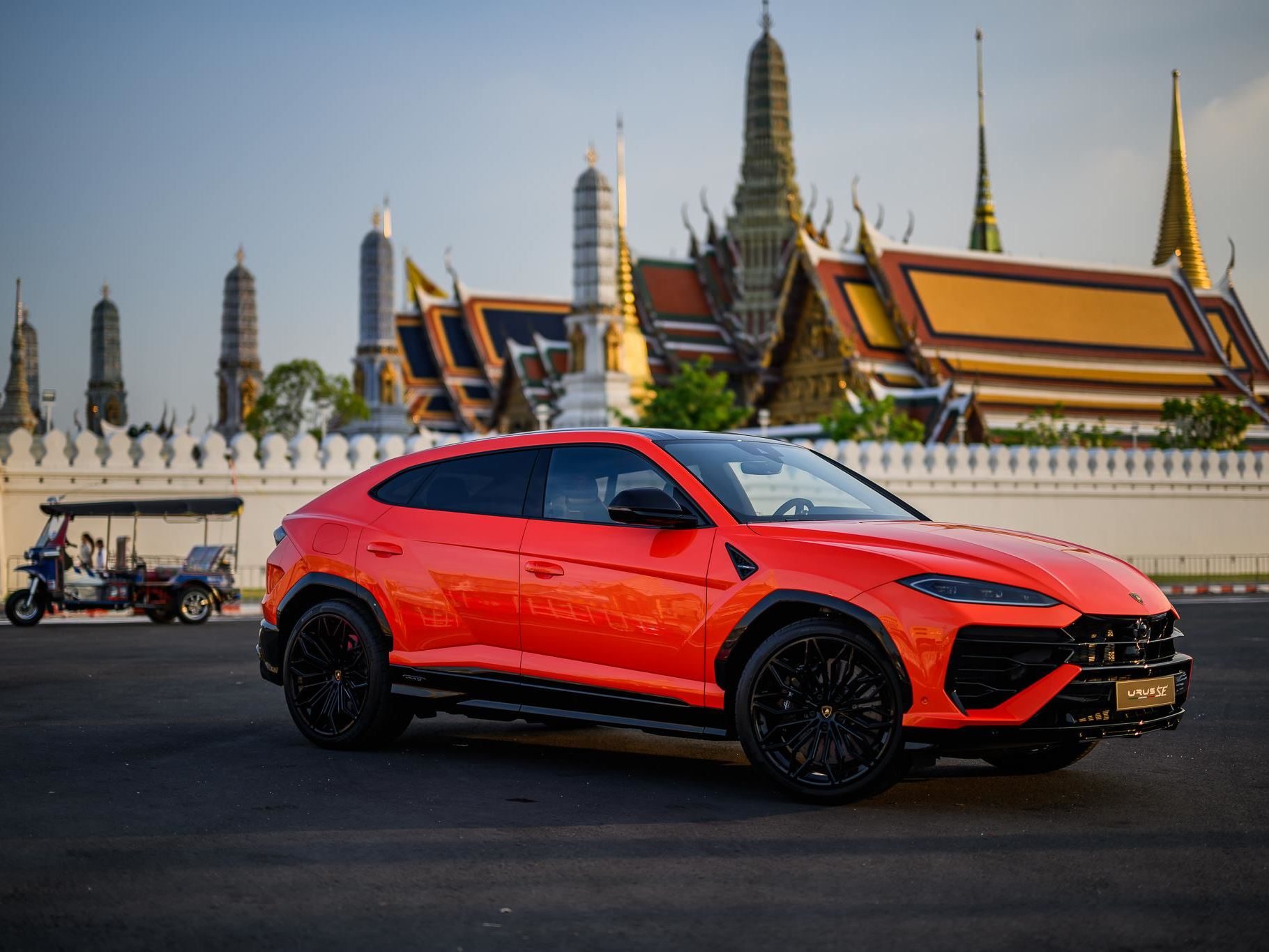 Lamborghini Brings The 800 Cv Urus Se To Bangkok, Pairing Plug-In Hybrid Power With Southeast Asian Ambition 7 Orange lamborghini urus se parked on asphalt with bangkok's grand palace in the background under a clear sky