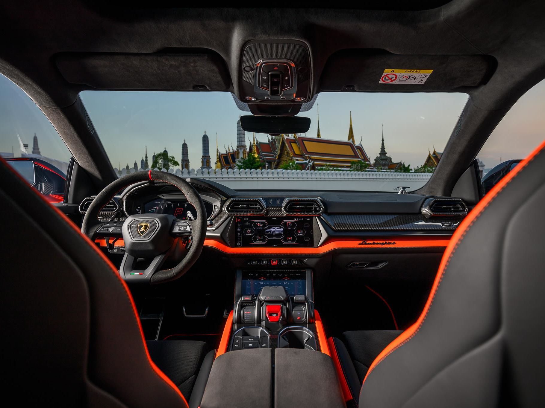 Lamborghini Brings The 800 Cv Urus Se To Bangkok, Pairing Plug-In Hybrid Power With Southeast Asian Ambition 11 Lamborghini urus se interior with black and orange color scheme, digital displays, and bangkok's grand palace visible through the windshield
