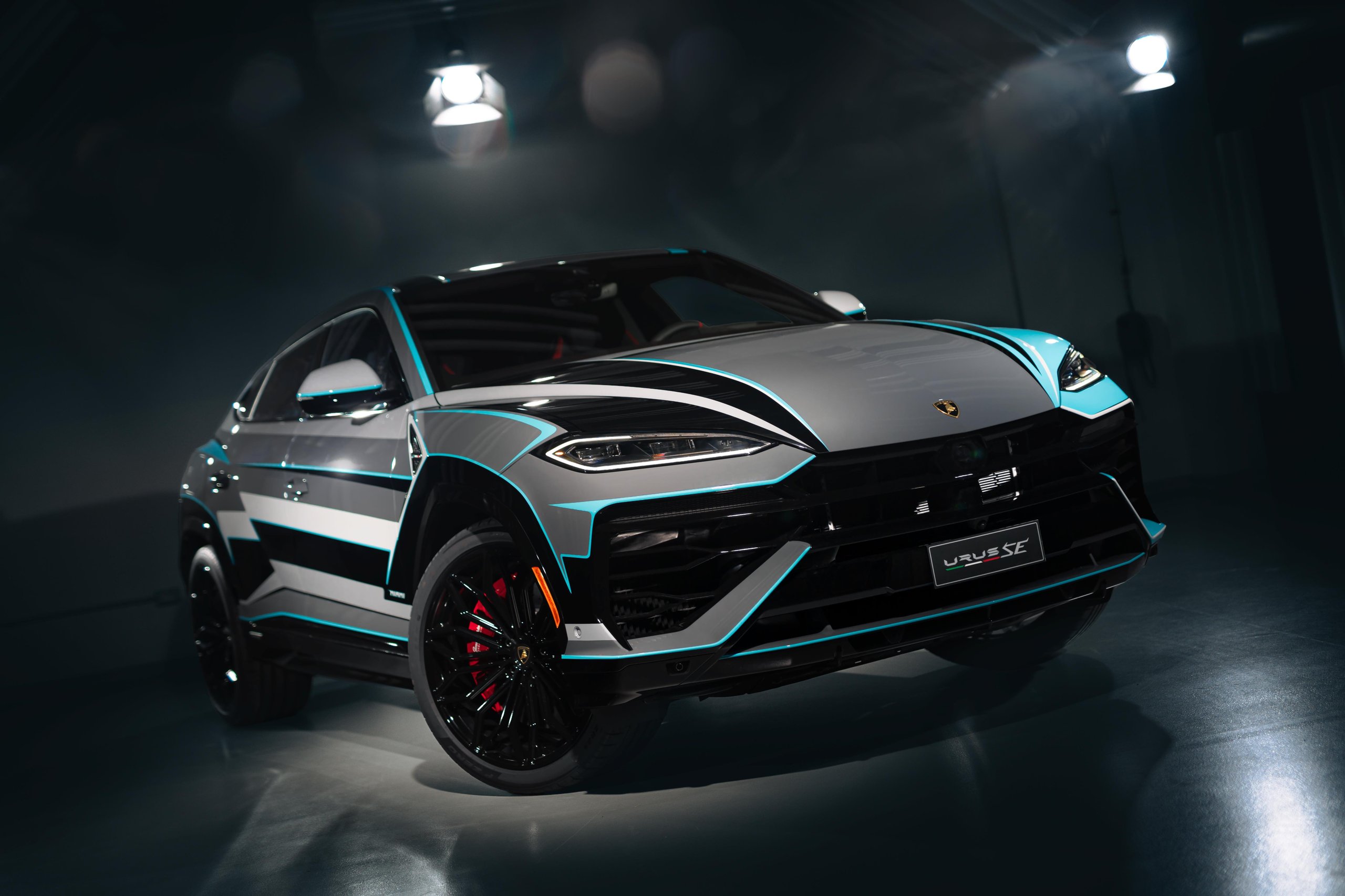 From Rambo Lambo To 800 Cv Hybrid: How Lamborghini Spent Half A Century Building The World'S Most Extreme Suv 9 A grey lamborghini urus se with a distinctive blue and white graphic livery showcasing its aggressive front design and illuminated headlights in a dark studio