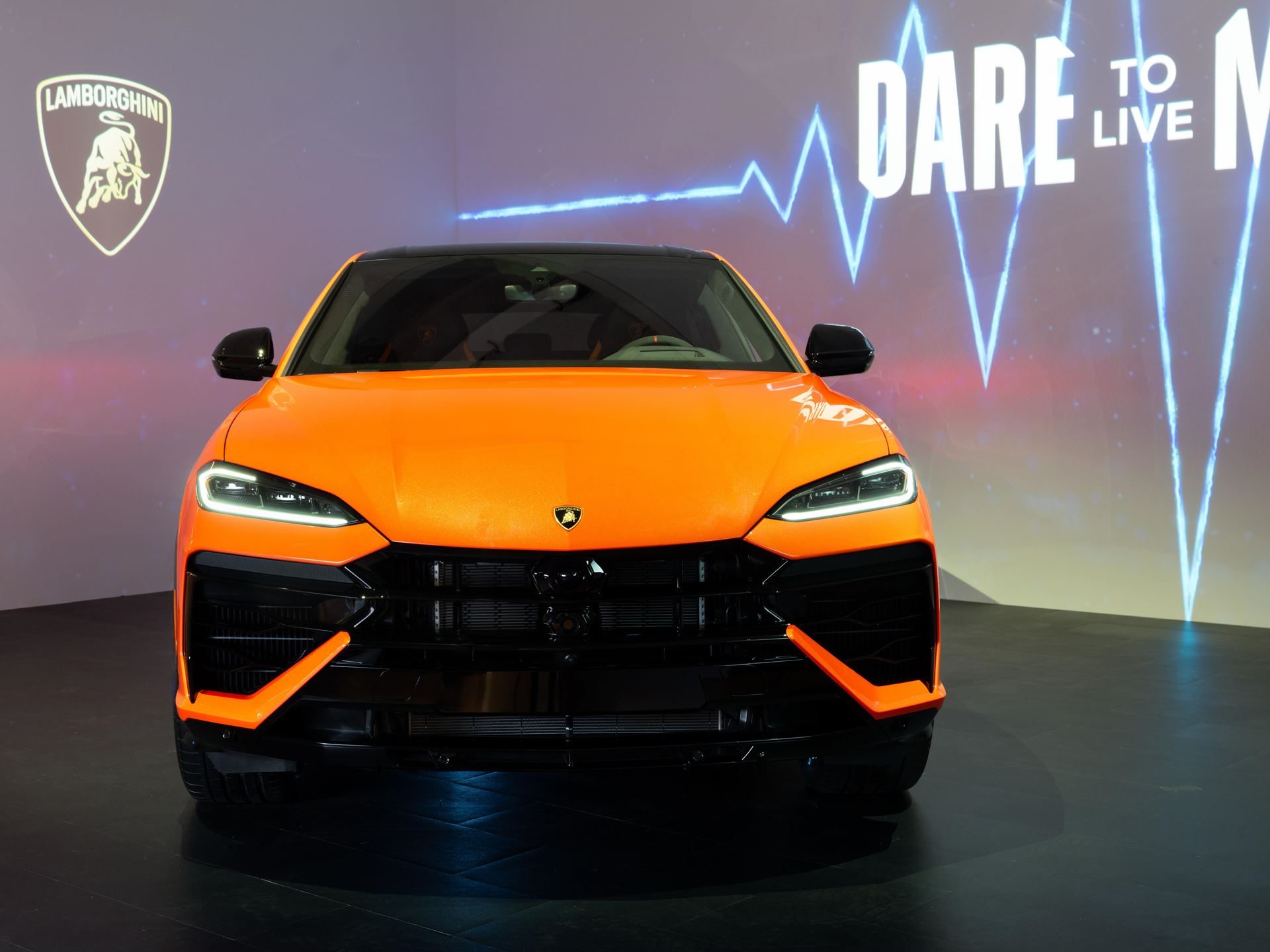 Lamborghini Brings The 789-Hp Urus Se To New York, Betting Its Best-Seller On Hybrid Power 5 Direct frontal view of the orange lamborghini urus se showing aggressive front design, hexagonal grille, and illuminated headlights