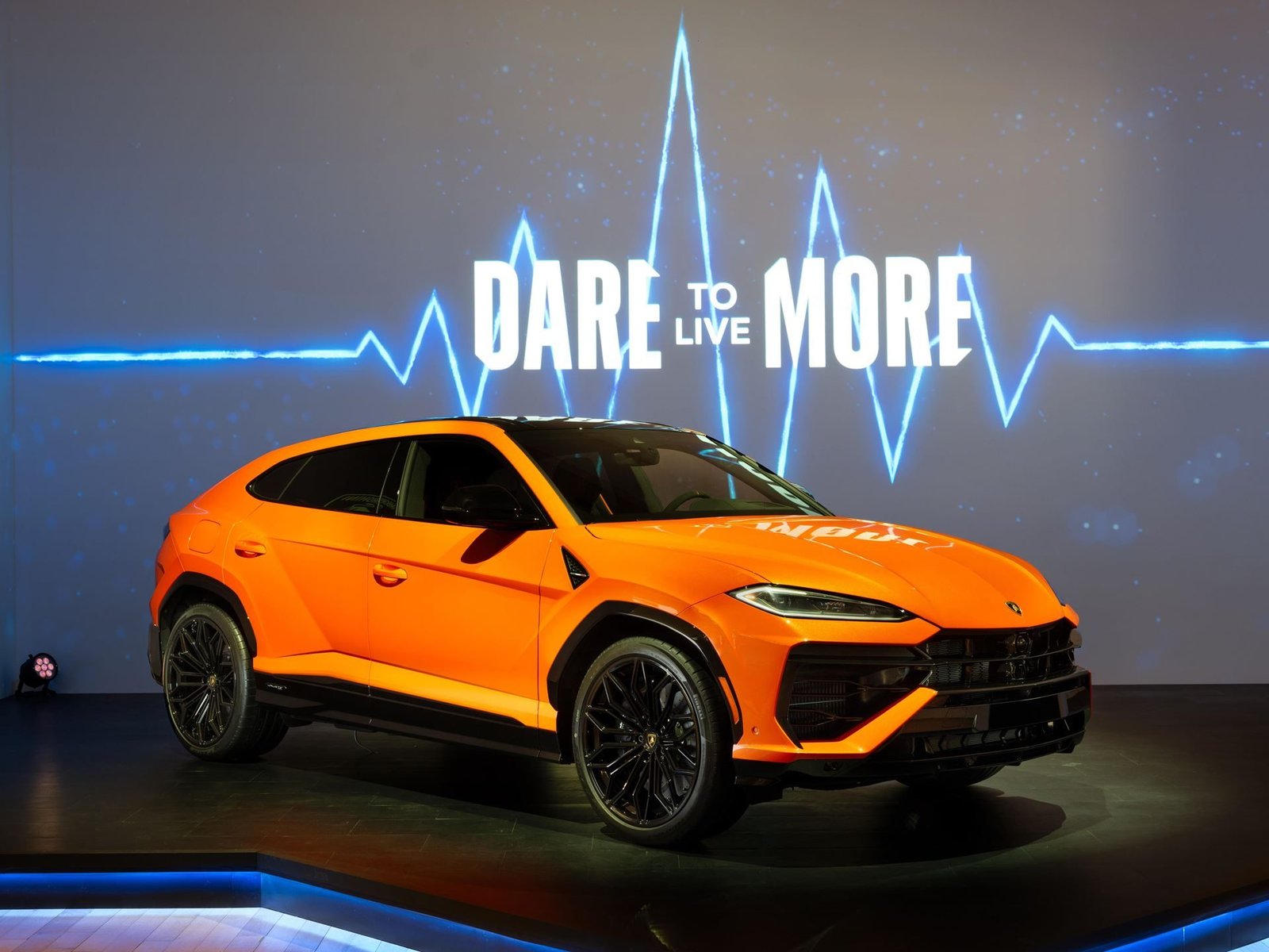 Orange Lamborghini Urus SE on display at the Lamborghini Lounge NYC with DARE TO LIVE MORE backdrop