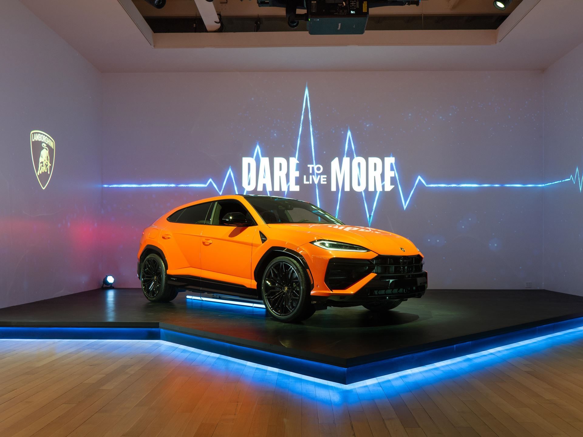 Lamborghini Brings The 789-Hp Urus Se To New York, Betting Its Best-Seller On Hybrid Power 11 Orange lamborghini urus se displayed on an illuminated platform at the nyc event with dare to live more graphic and lamborghini logo