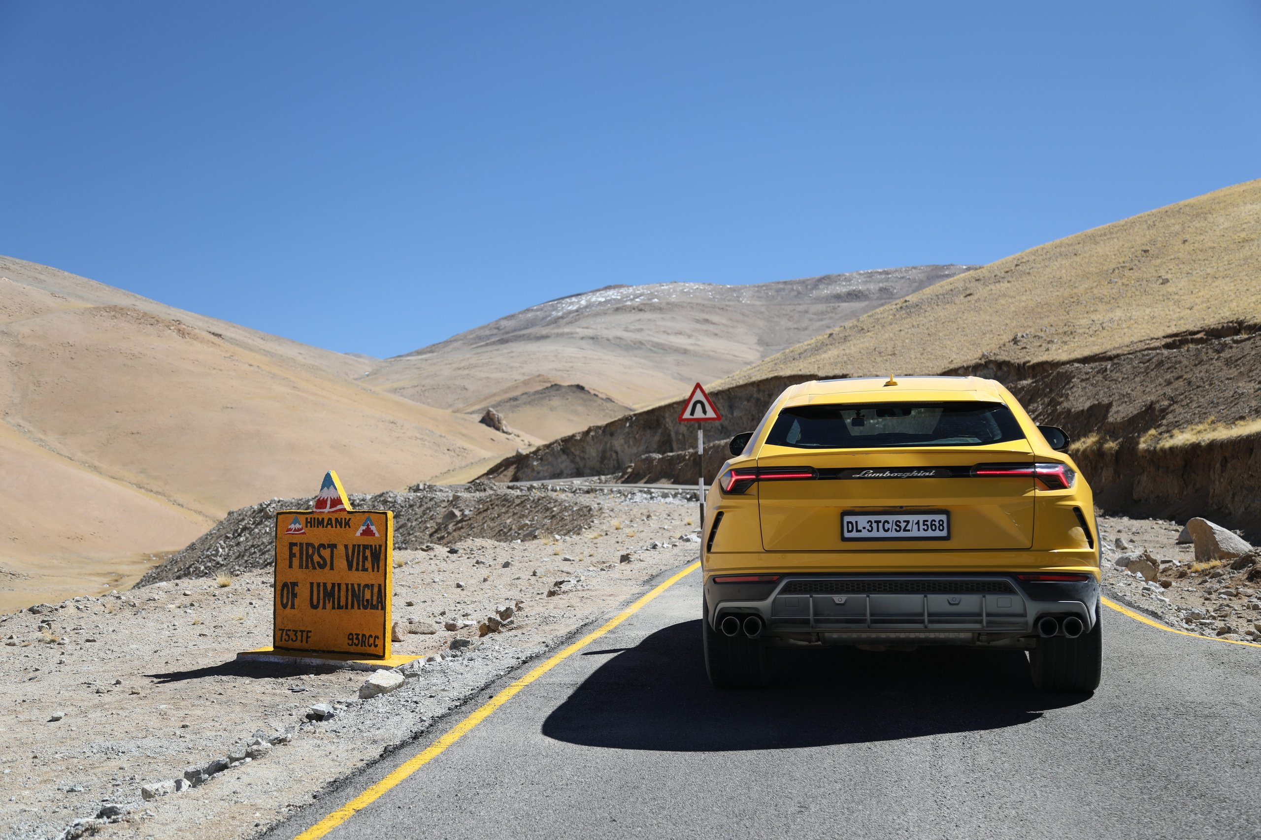 The Lamborghini Urus At 19,300 Feet: Conquering The World'S Highest Drivable Road 9 Rear view of yellow lamborghini urus on a mountain road with first view of umlingla sign visible