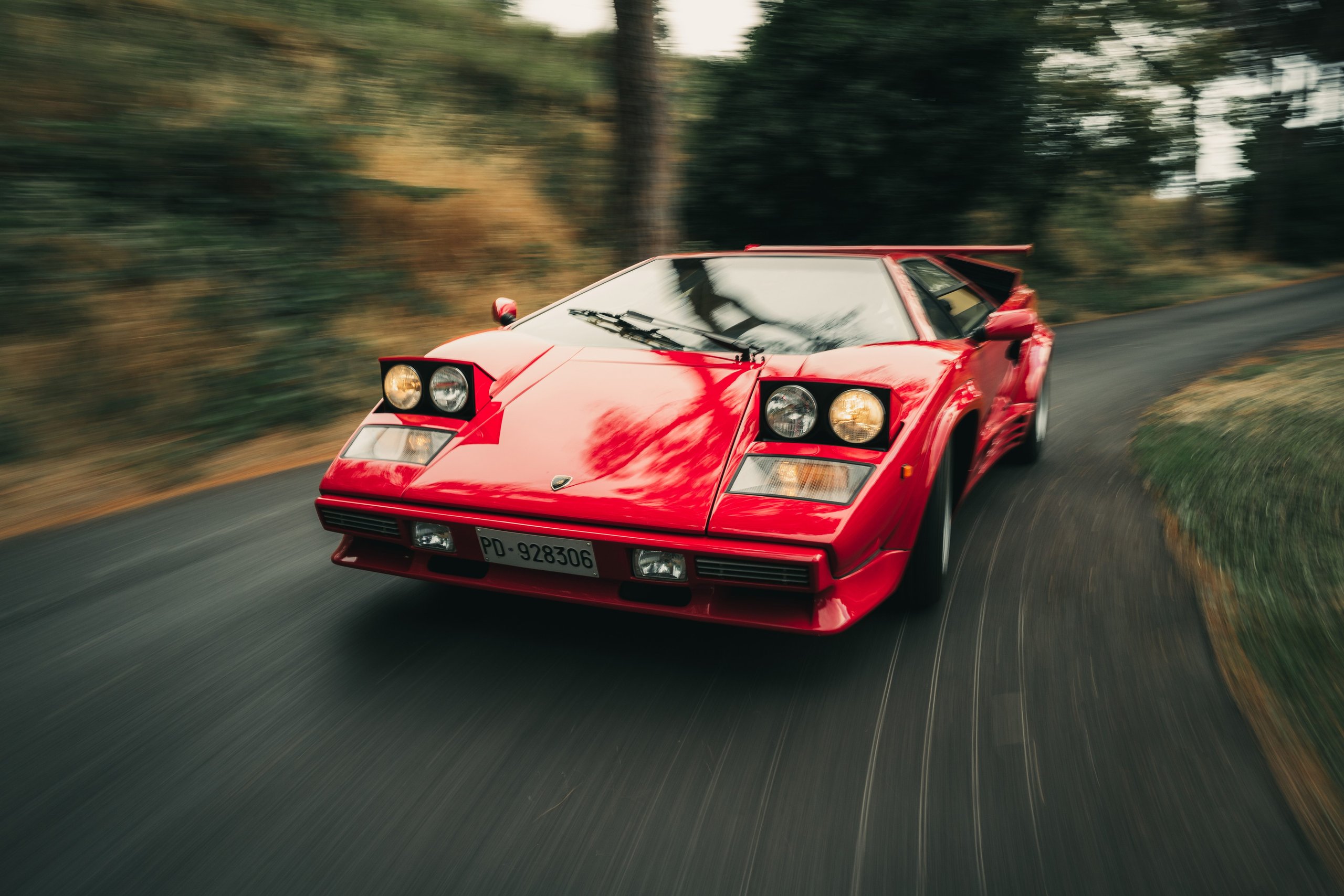 One V12, Two Wildly Different Lamborghinis: How The Countach And Lm 002 Proved The Twelve-Cylinder Could Do Anything 5 Red lamborghini countach lp5000 qv driving at speed on a winding road with motion blur in background