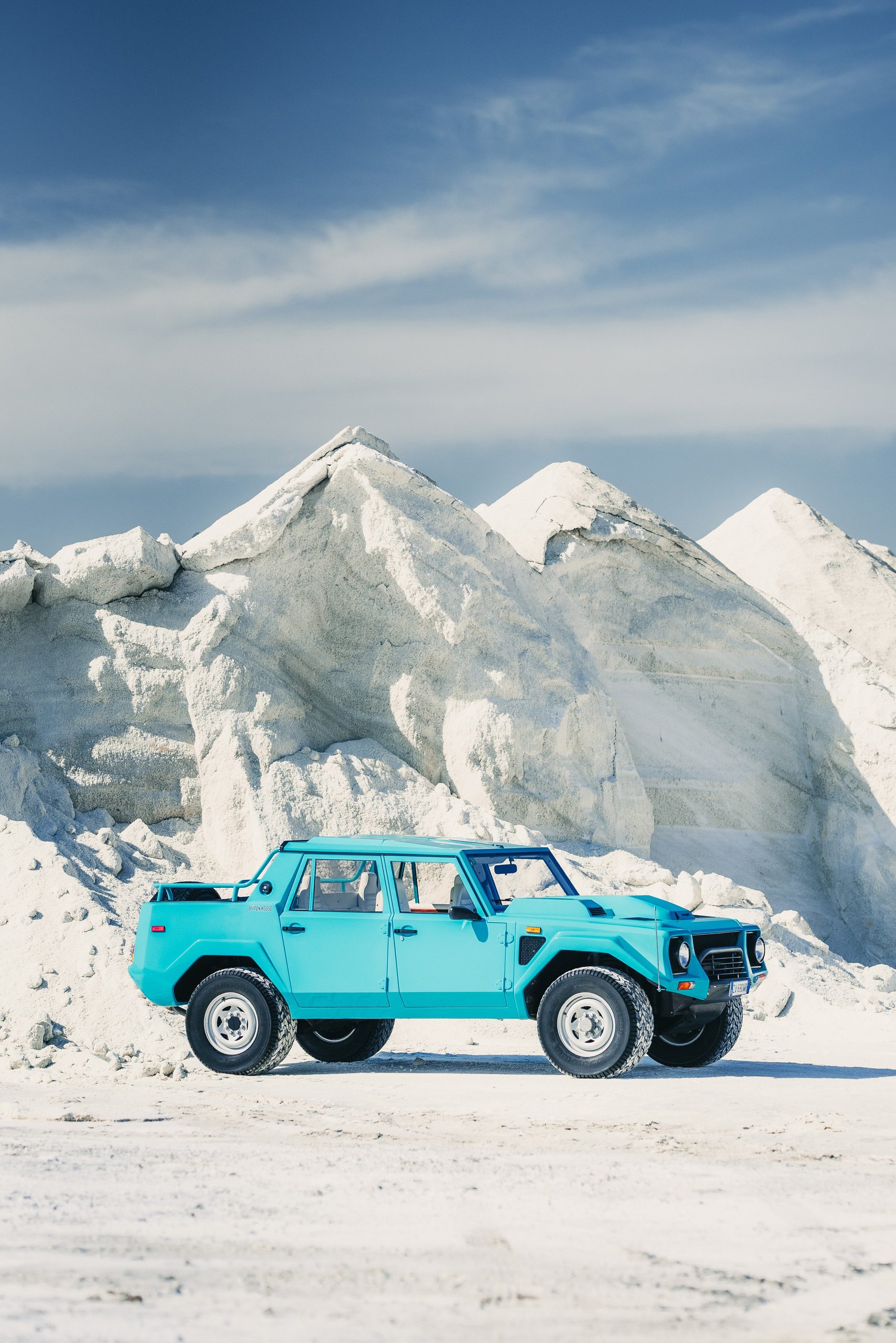 One V12, Two Wildly Different Lamborghinis: How The Countach And Lm 002 Proved The Twelve-Cylinder Could Do Anything 7 Teal lamborghini lm 002 parked in a sandy desert landscape with white rock formations under blue sky