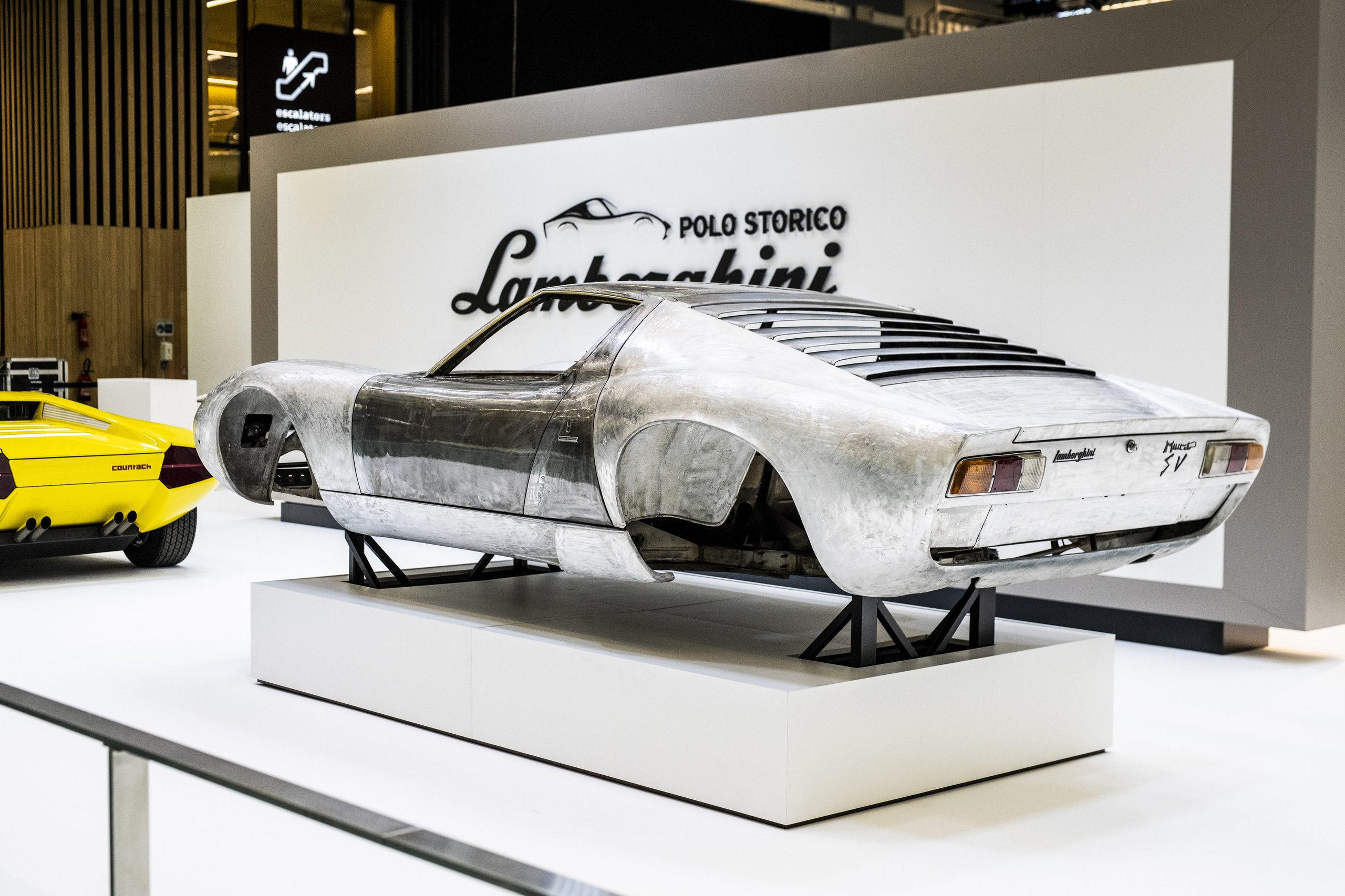 25,000 Hours To Build A Bridge: How Polo Storico'S Resurrected Countach Lp 500 Frames Lamborghini'S Hybrid V12 Future 7 Bare metal lamborghini miura p400 sv body shell on display at rétromobile with yellow countach visible behind