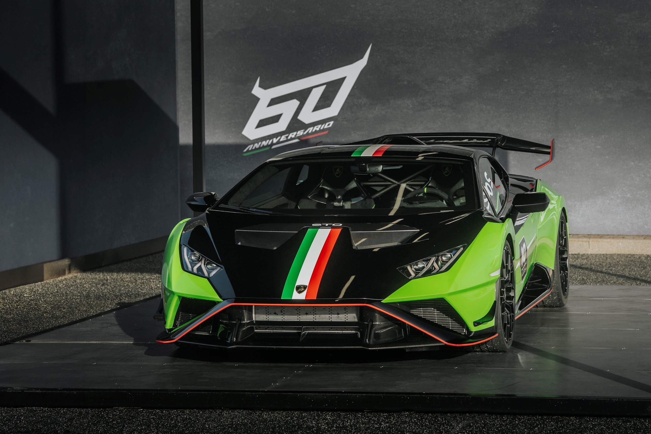 Green and black lamborghini huracán sto sc 10th anniversario with italian flag stripe displayed in front of 60 anniversario branding