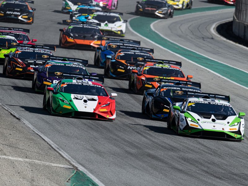 Multiple Lamborghini Huracán GT3 EVO race cars competing on track in close formation, one wearing Italian flag livery
