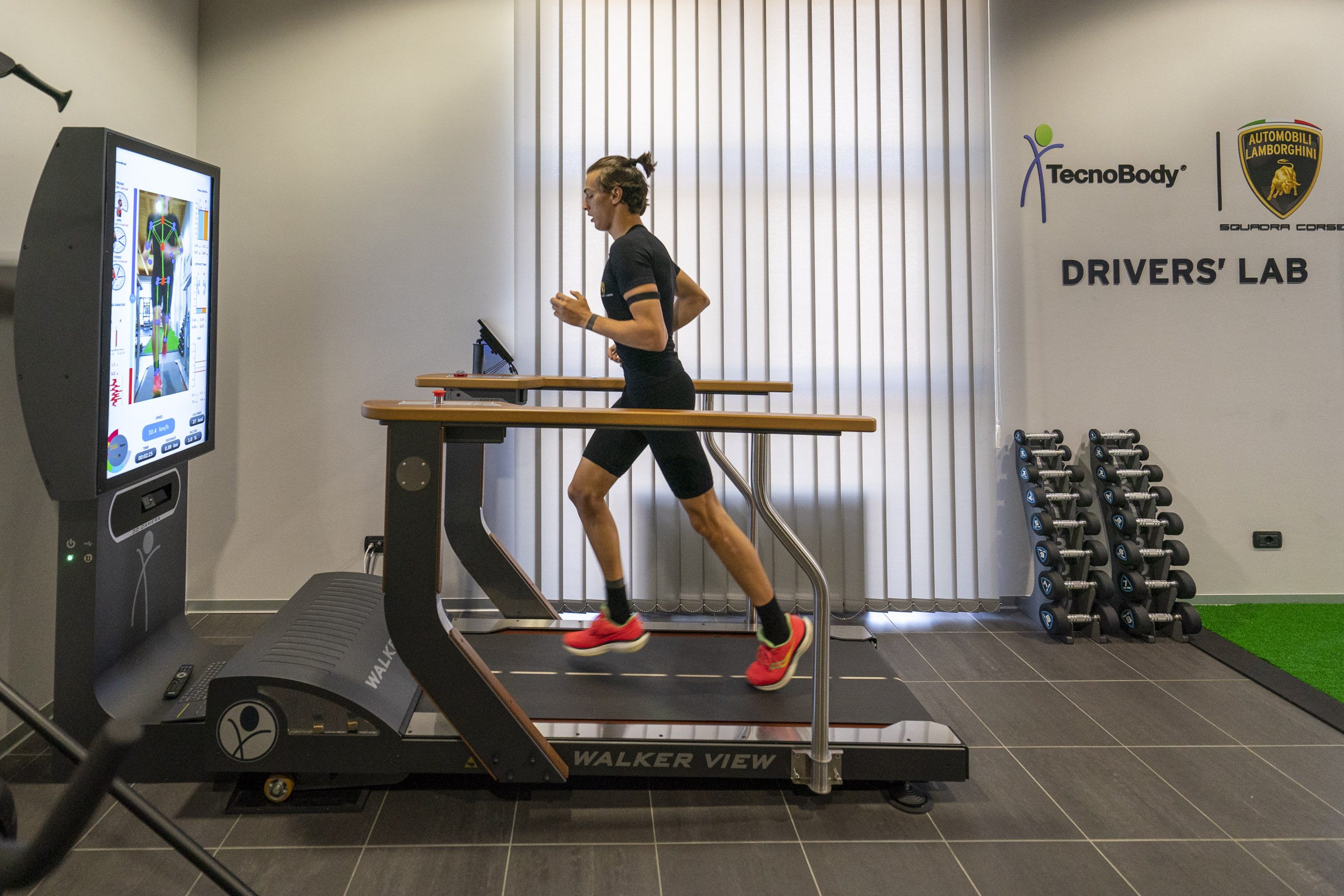 An athlete running on a walker view treadmill in the lamborghini drivers' lab, with lamborghini branding on the wall behind