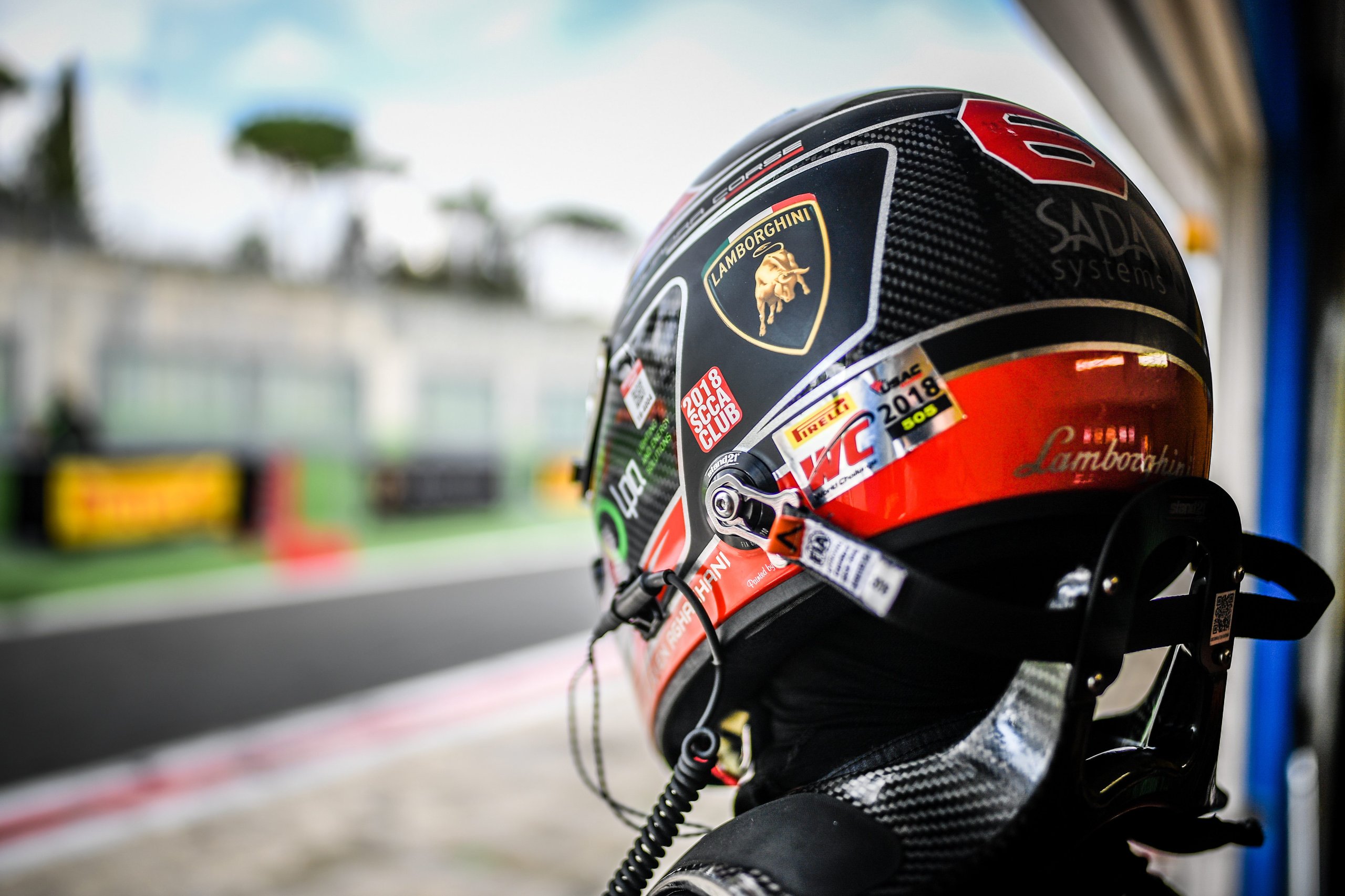 34 Aspiring Racers, One Factory Seat: Inside Squadra Corse'S Talent Pipeline For 2021 3 Close-up of a racing helmet with lamborghini and sponsor logos, driver gazing toward a blurred race track