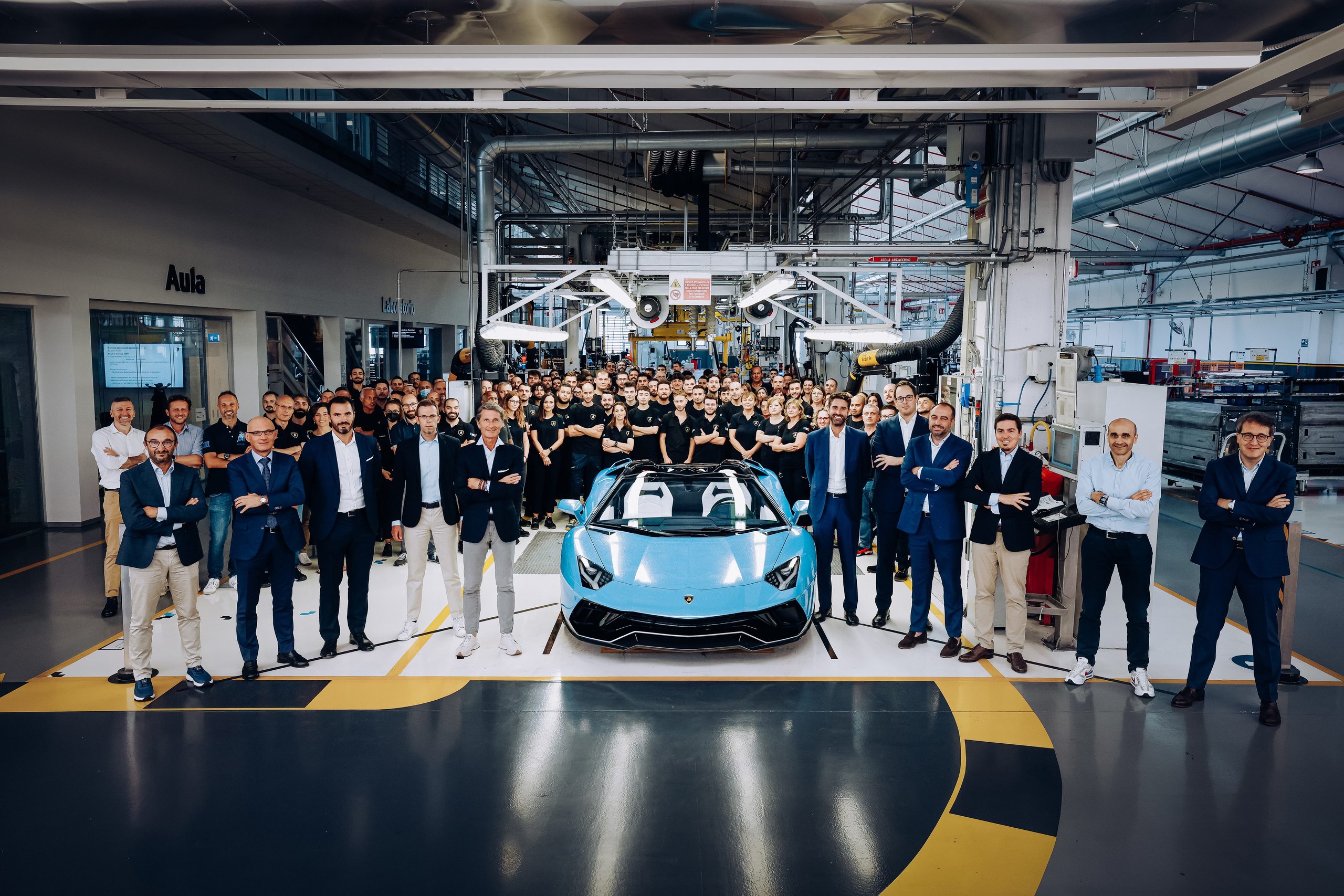 The Last Pure V12 Lamborghini Rolled Off The Line In Light Blue, And Nothing Will Replace What It Represented 3 Large group of lamborghini employees posing around the final light blue aventador ultimae roadster on the factory floor