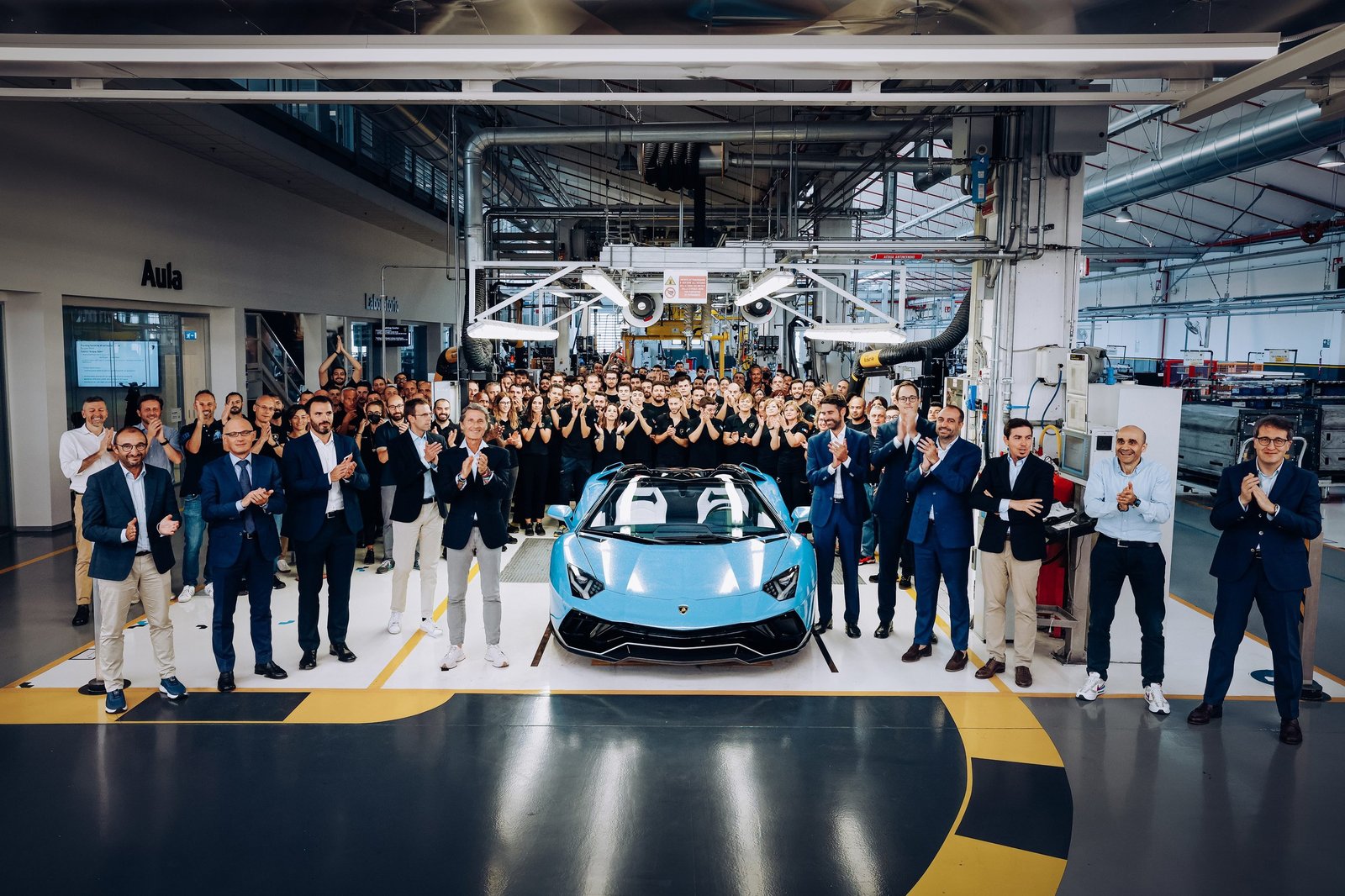 Lamborghini employees and executives applauding around the final light blue Aventador LP 780-4 Ultimae Roadster on the factory floor in Sant'Agata Bolognese