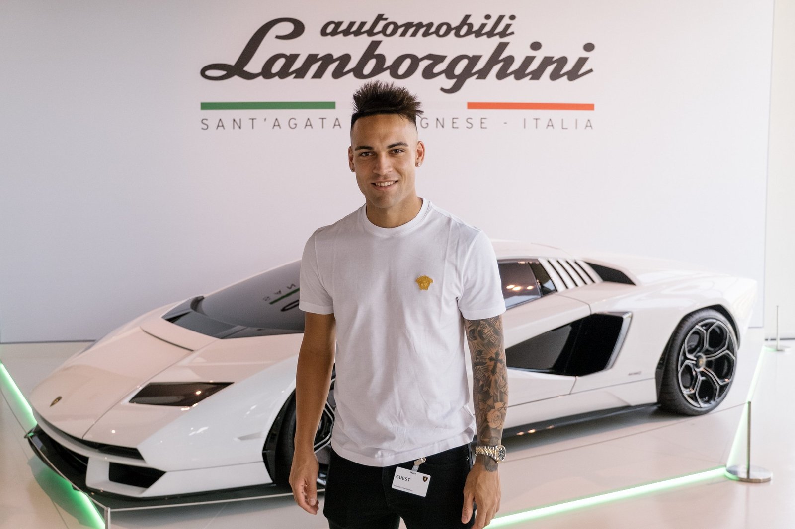 Lautaro Martinez standing in the Lamborghini showroom in front of a white Countach LPI 800-4 with the Automobili Lamborghini logo on the wall behind him