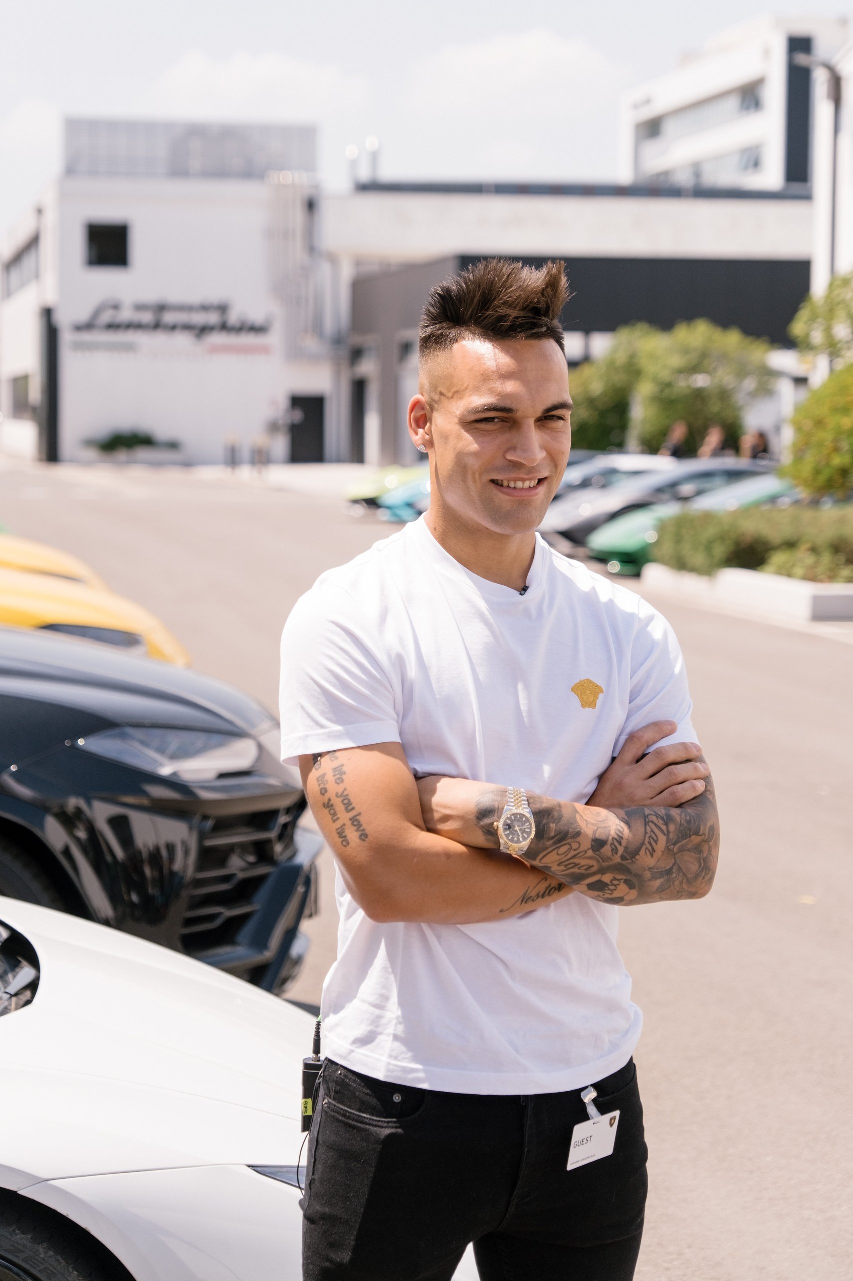 Inside Lautaro Martinez'S Bespoke Urus Configuration At Lamborghini'S Sant'Agata Factory 3 Lautaro martinez standing outdoors with arms crossed and smiling, with several lamborghini urus suvs and the lamborghini factory building behind him
