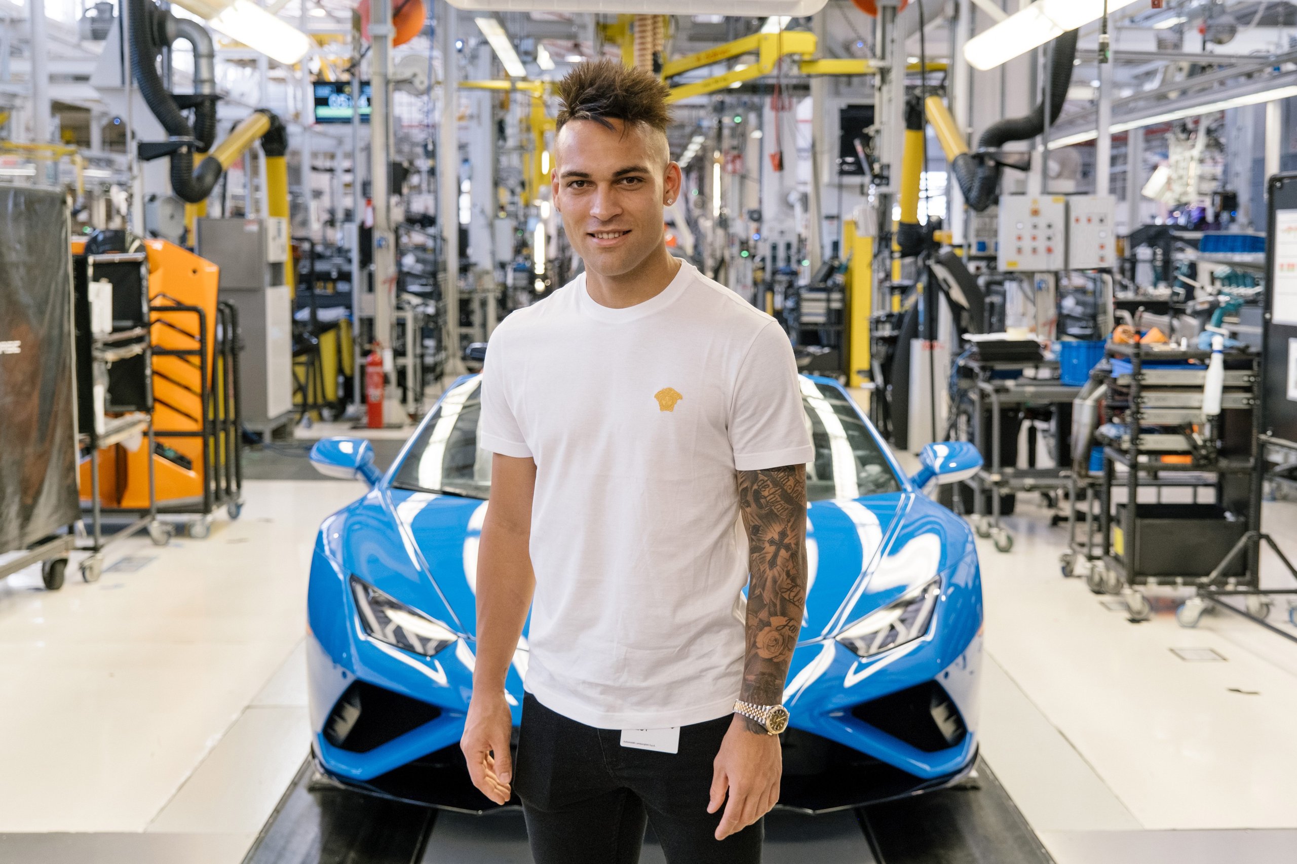 Inside Lautaro Martinez'S Bespoke Urus Configuration At Lamborghini'S Sant'Agata Factory 5 Lautaro martinez standing in front of a blue lamborghini huracán on the factory assembly line, with overhead equipment and factory infrastructure visible