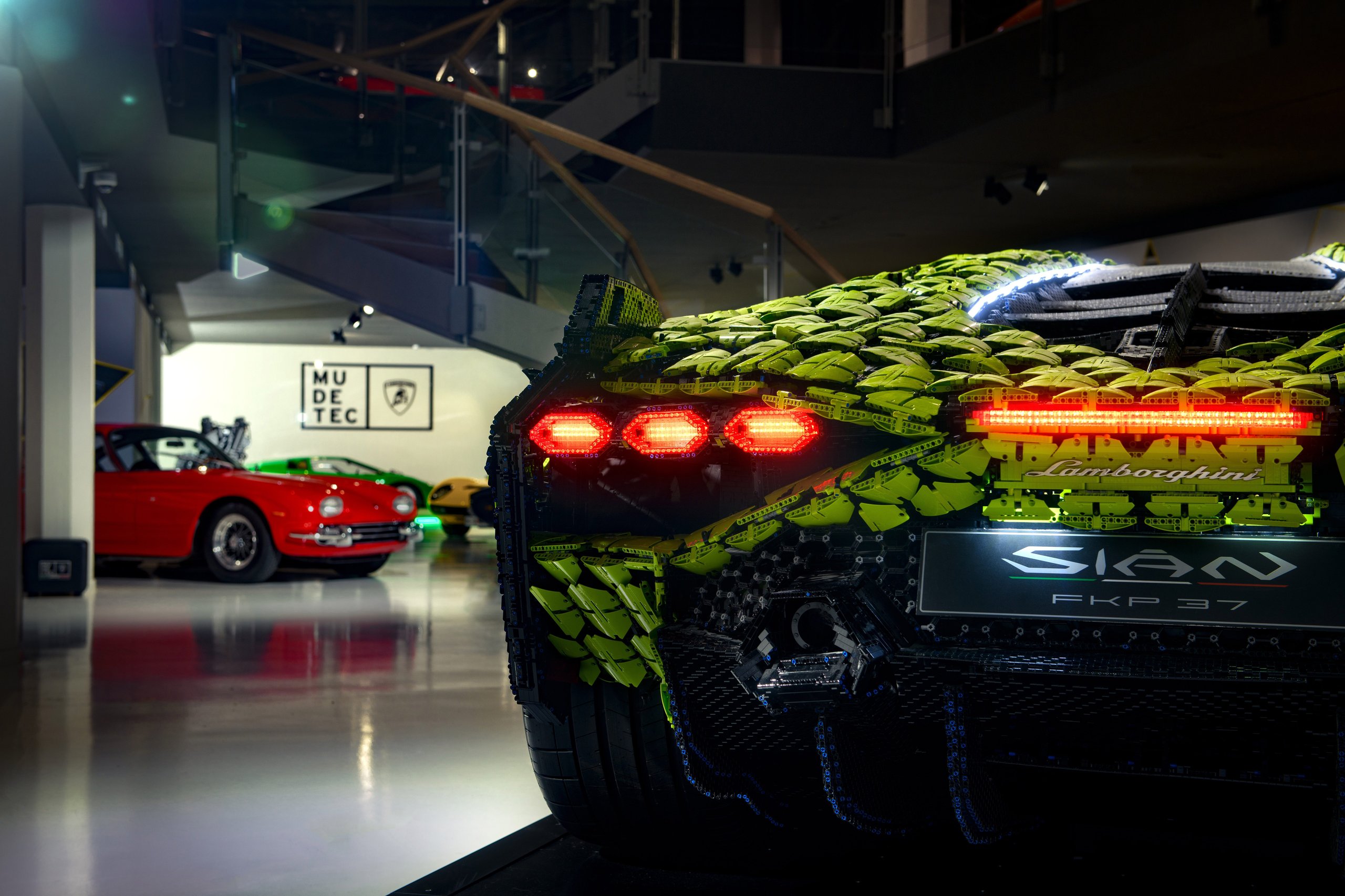 400,000 Bricks, One Sián: Inside The Life-Size Lego Technic Lamborghini That Got Painted In Sant'Agata 5 Rear three-quarter view of the life-size lego technic lamborghini sián fkp 37 showing illuminated hexagonal taillights, lamborghini badging, and classic lamborghini models visible in the museum background.