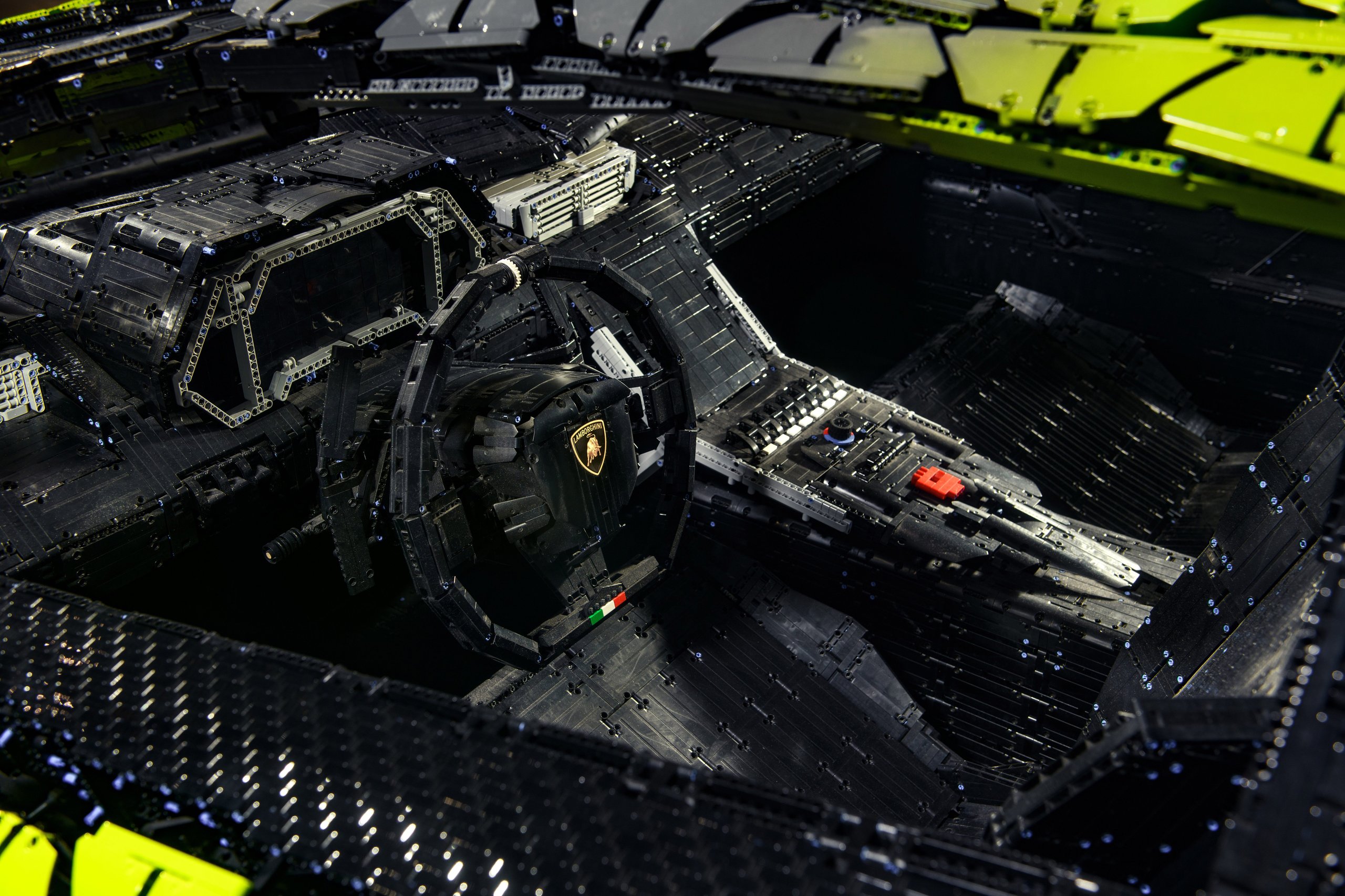 400,000 Bricks, One Sián: Inside The Life-Size Lego Technic Lamborghini That Got Painted In Sant'Agata 7 Overhead view of the life-size lego technic sián's interior showing the steering wheel with lamborghini emblem and italian flag detail, dashboard, and center console, all constructed from lego bricks.