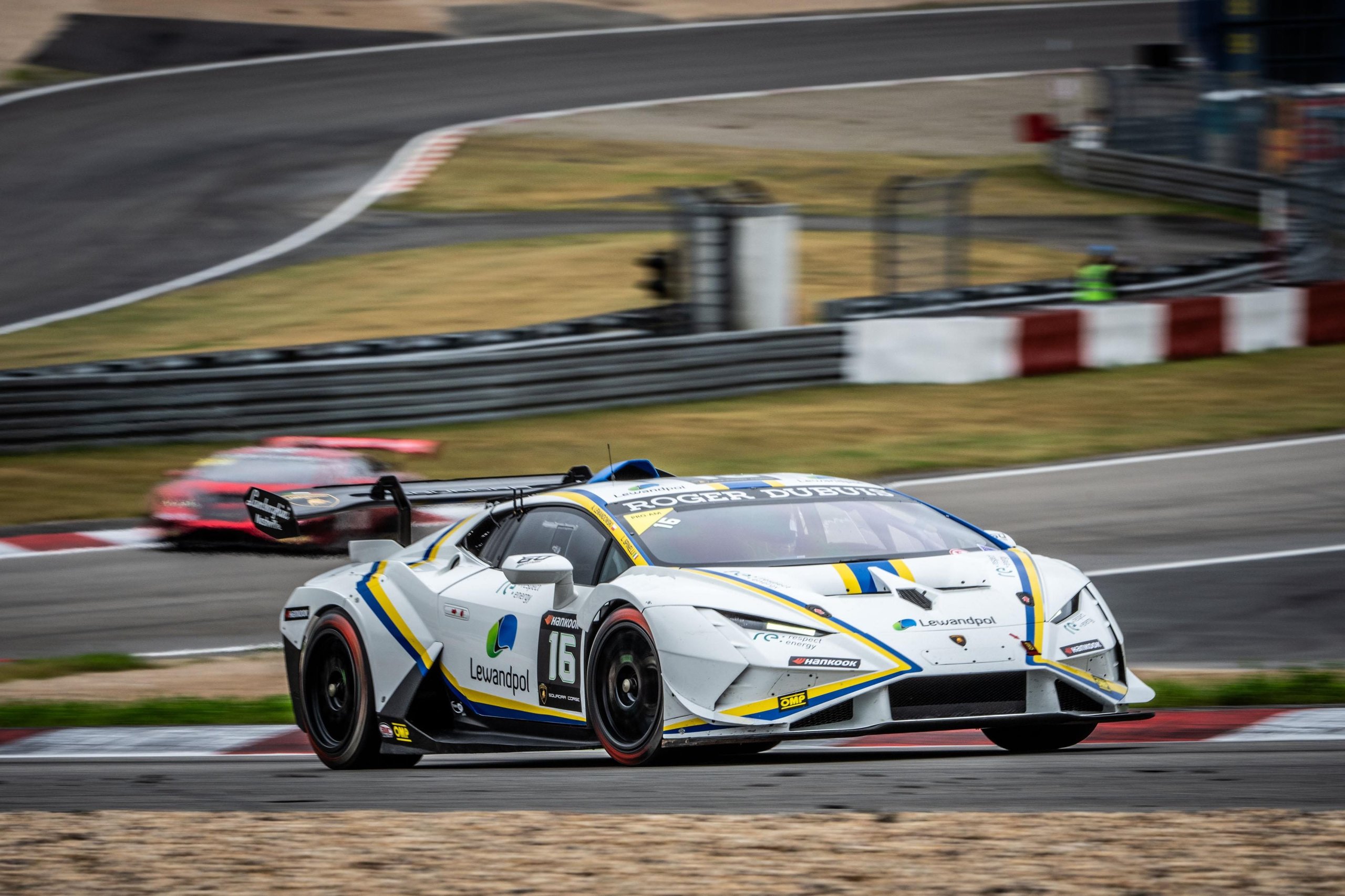 Brendon Leitch'S Late-Race Dummy Move At Nürburgring Delivers Leipert Motorsport'S First Overall Super Trofeo Win 3 White lamborghini huracán super trofeo evo2 with blue and yellow accents racing through a corner at nürburgring