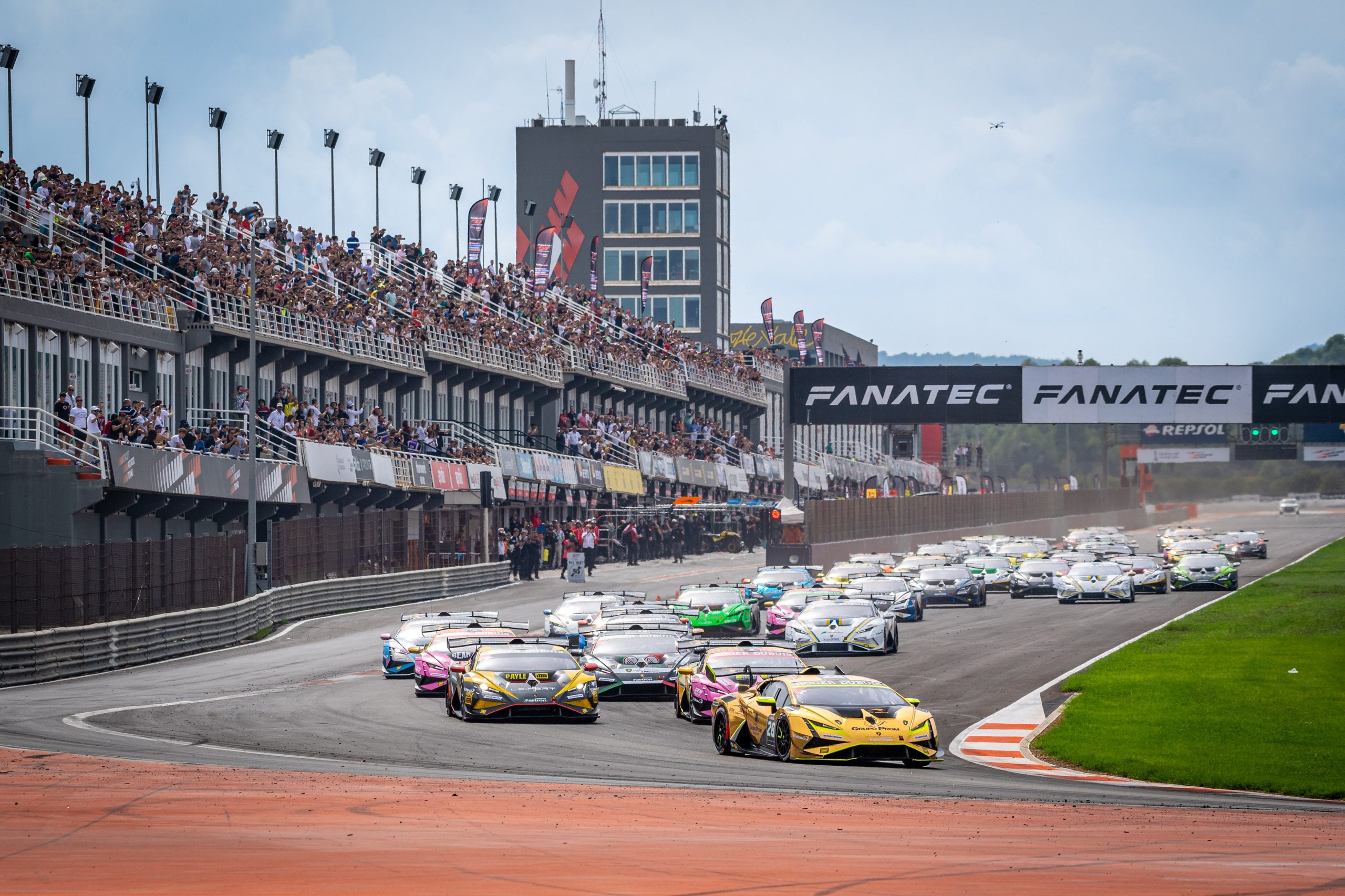 A packed grid of lamborghini huracán super trofeo evo2 race cars lines up on the valencia circuit with spectators in the grandstands