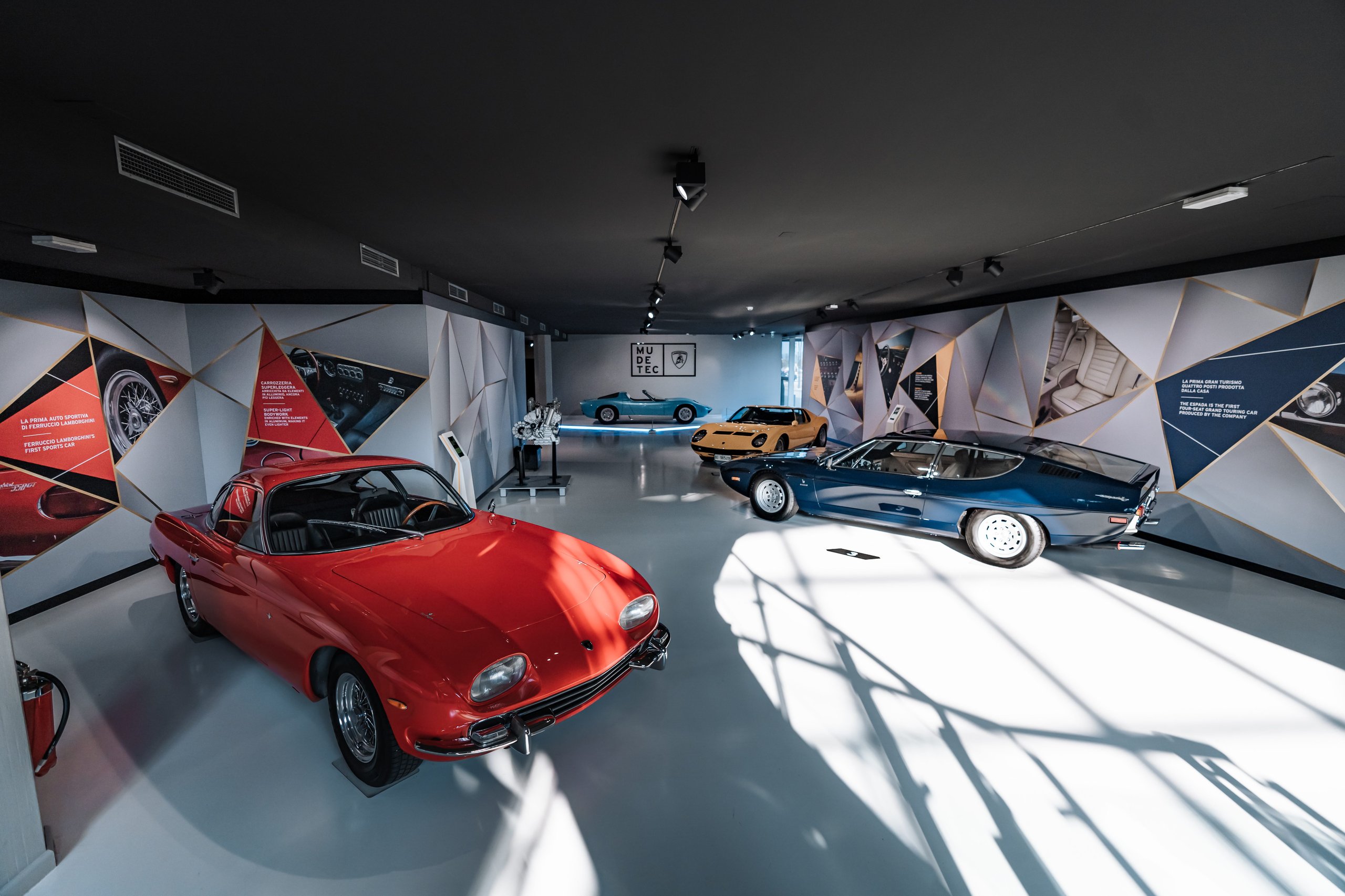 The 1968 Miura Roadster Returns To Mudetec, And Its Design Dna Lives In The Aventador Ultimae'S Final Bow 9 Wide shot of the mudetec museum interior showing multiple classic lamborghini models including the miura roadster, a yellow miura coupe, a red 400 gt, and a blue islero