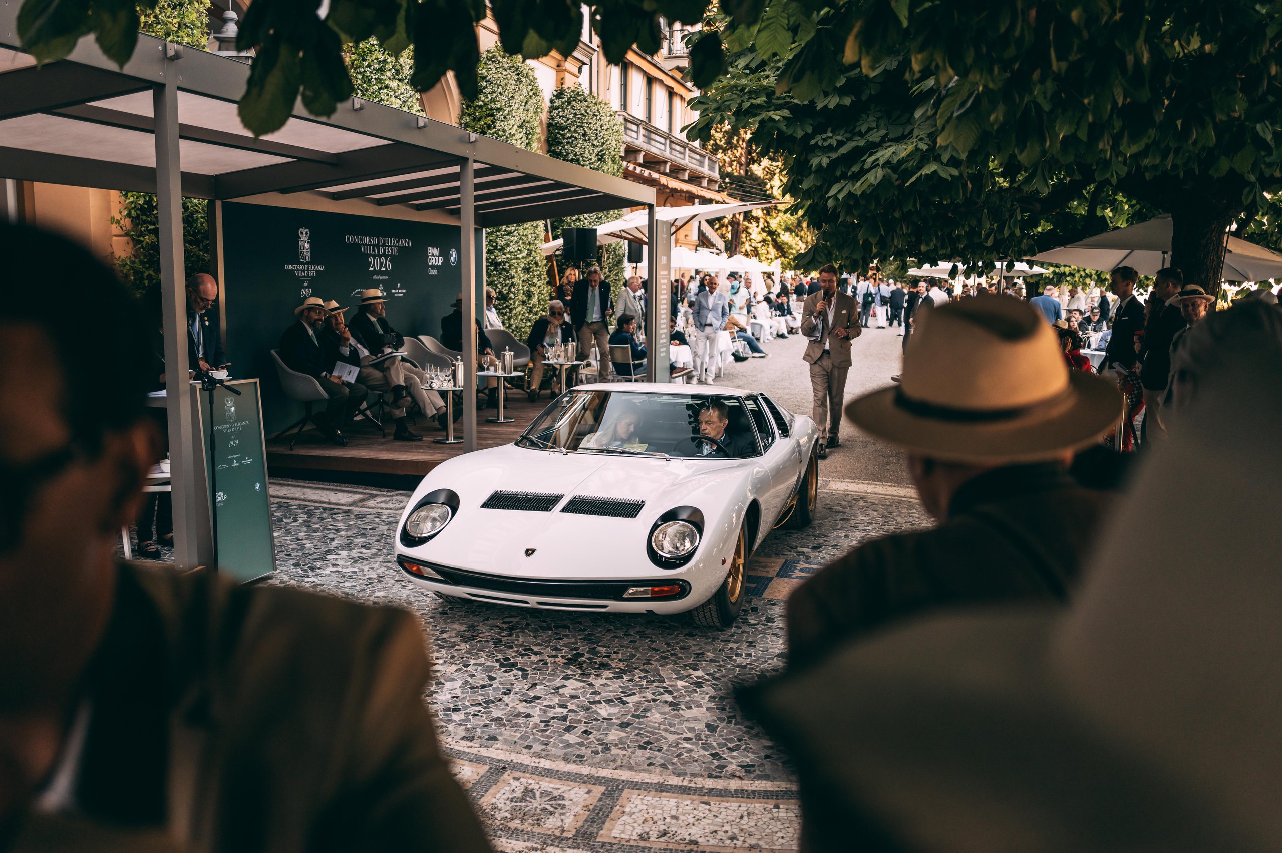 A 1971 Miura Sv Just Won At Villa D'Este, And Its 60Th Anniversary Timing Could Not Be Better 7 White lamborghini miura sv driving on cobblestones at villa d'este, viewed past a spectator