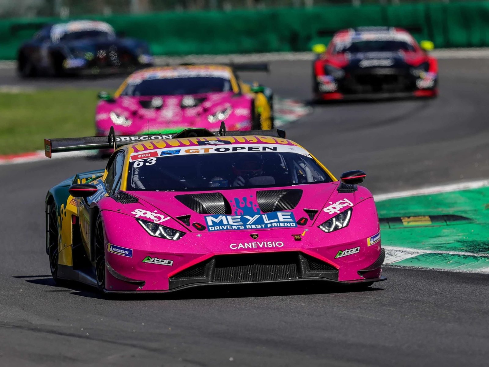 The #63 Oregon Team Lamborghini Huracán GT3 EVO2 in pink and yellow livery leads a pack of GT3 cars on track at Monza