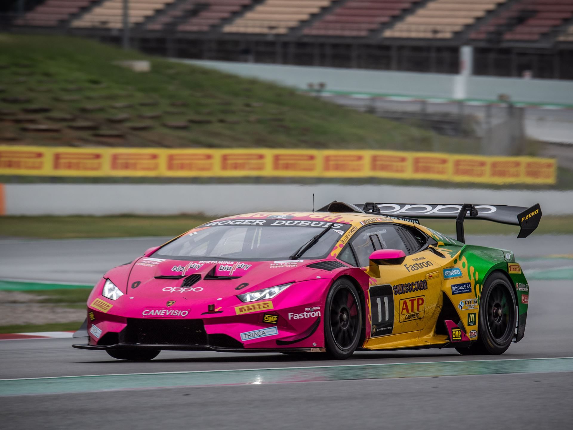 Oregon Team's #11 Lamborghini Huracán Super Trofeo EVO racing on wet tarmac at Barcelona with its distinctive multi-color livery and large rear wing visible