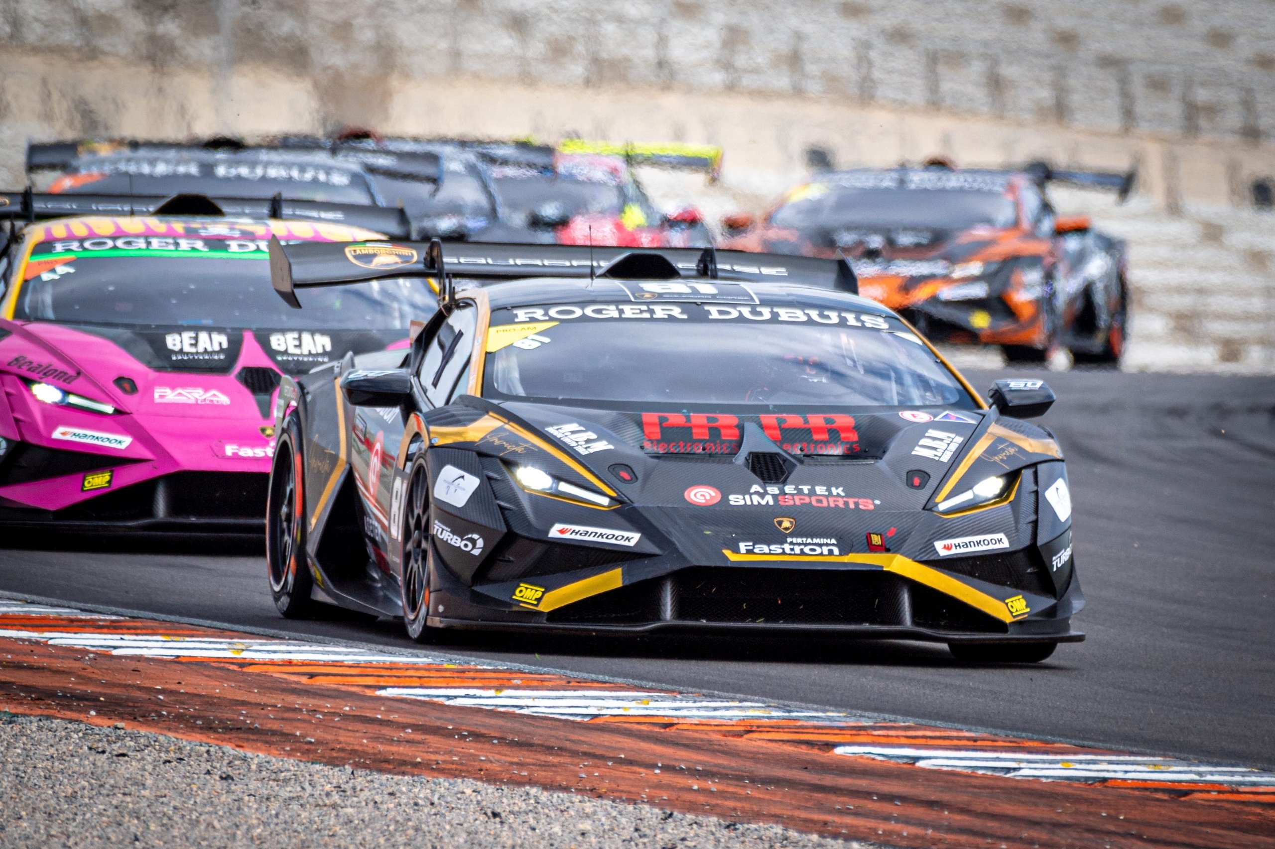 A black and yellow Lamborghini Huracán Super Trofeo EVO2 leads a pack of race cars through a turn at Valencia