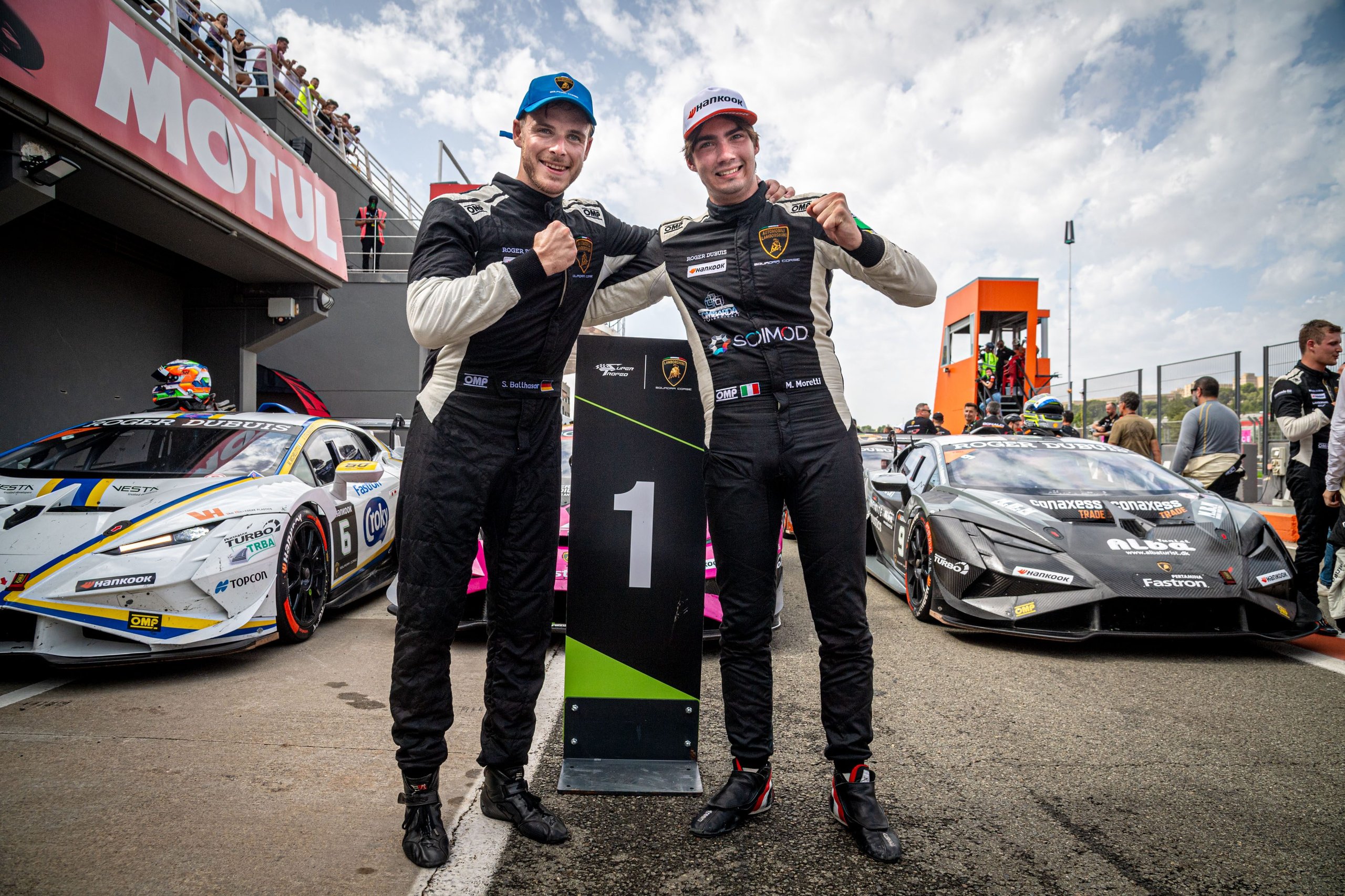 Moretti and Balthasar celebrate next to the number 1 stand in the pit lane with their Huracán Super Trofeo EVO2 race cars