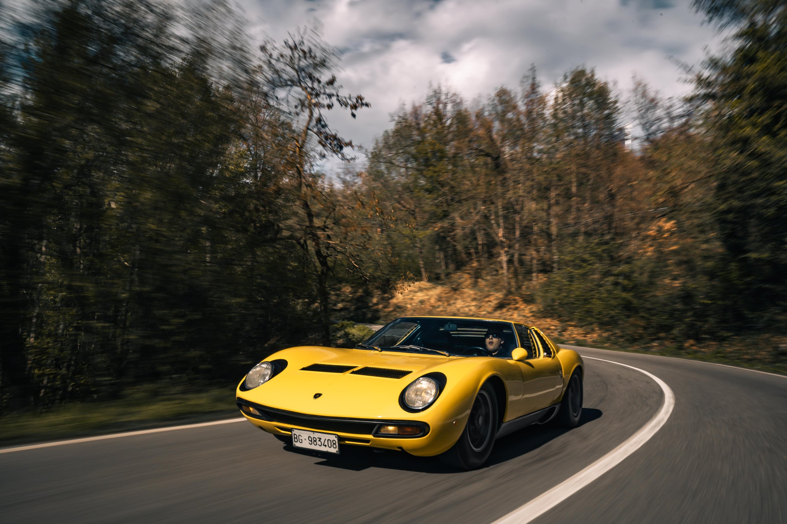 Polo Storico'S Oldest Surviving Lamborghini And A 2026 Miura Tour Signal Where The Brand'S Heritage Strategy Is Heading 9 Yellow lamborghini miura sv driving dynamically on a winding mountain road surrounded by autumn trees