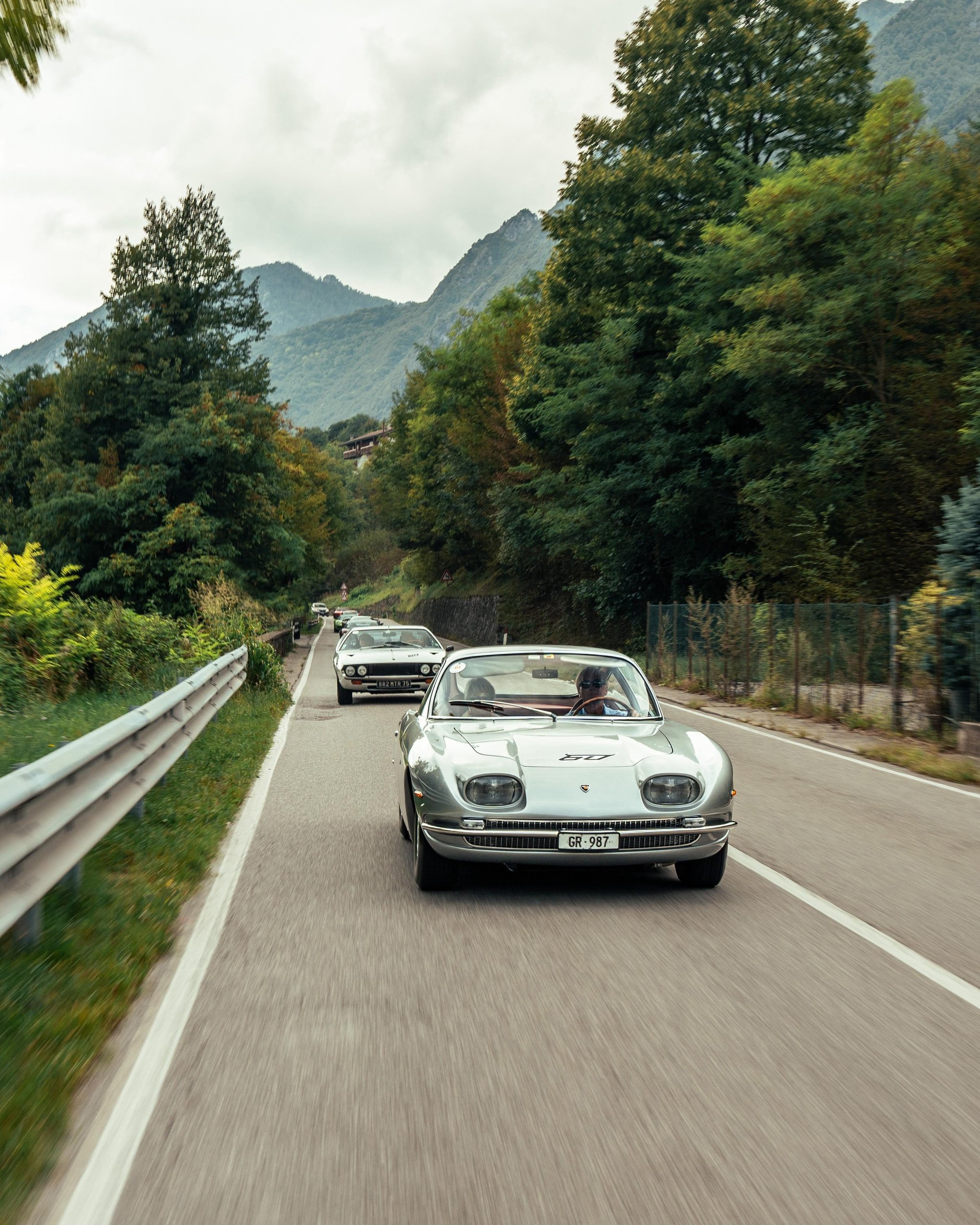 Polo Storico'S Oldest Surviving Lamborghini And A 2026 Miura Tour Signal Where The Brand'S Heritage Strategy Is Heading 13 Silver lamborghini islero convertible leads a convoy of classic lamborghinis on a winding mountain road with distant peaks