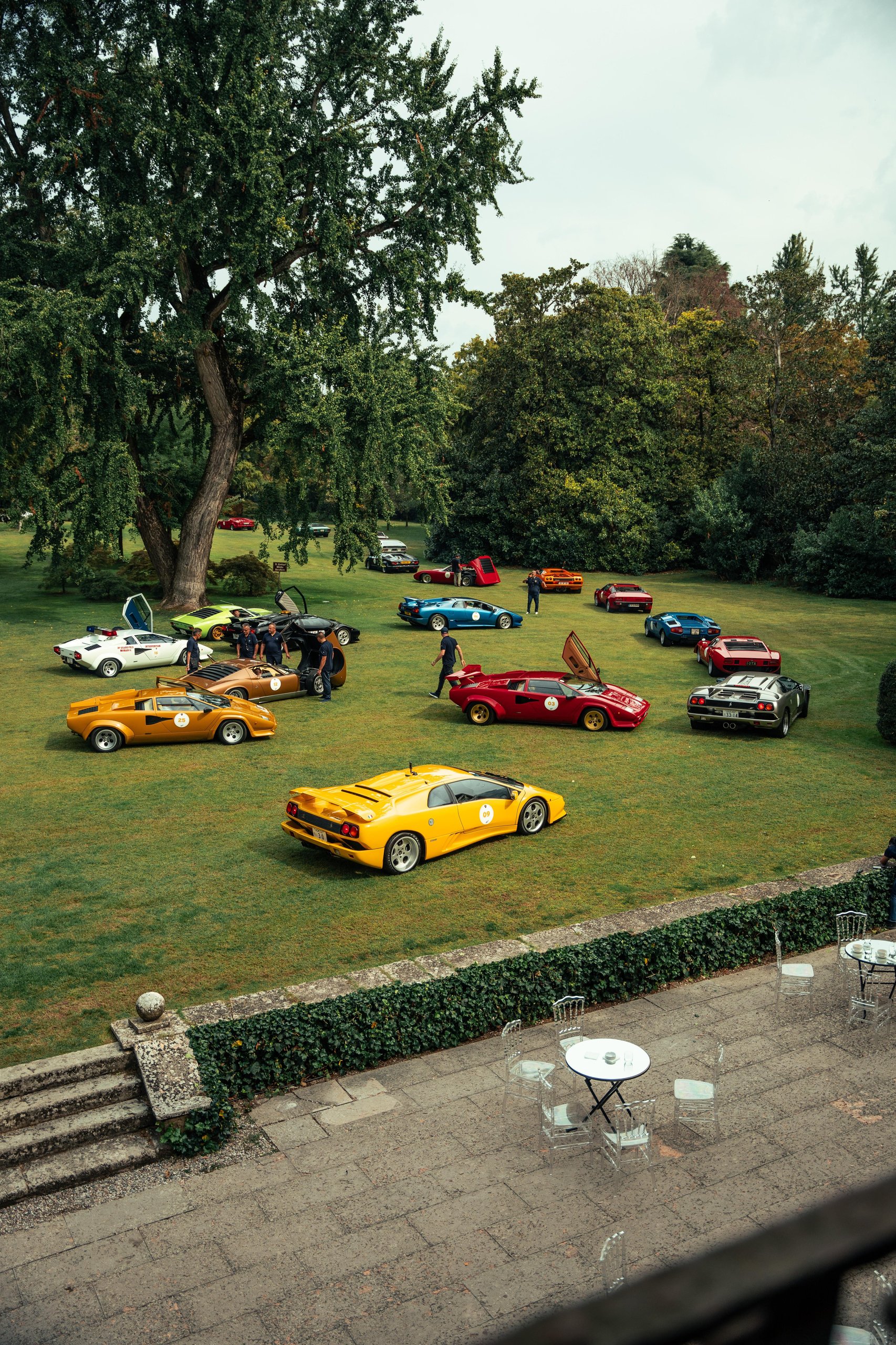 Polo Storico'S Oldest Surviving Lamborghini And A 2026 Miura Tour Signal Where The Brand'S Heritage Strategy Is Heading 11 Aerial view of a large gathering of classic lamborghini cars including diablos, countaches, and miuras on a green lawn