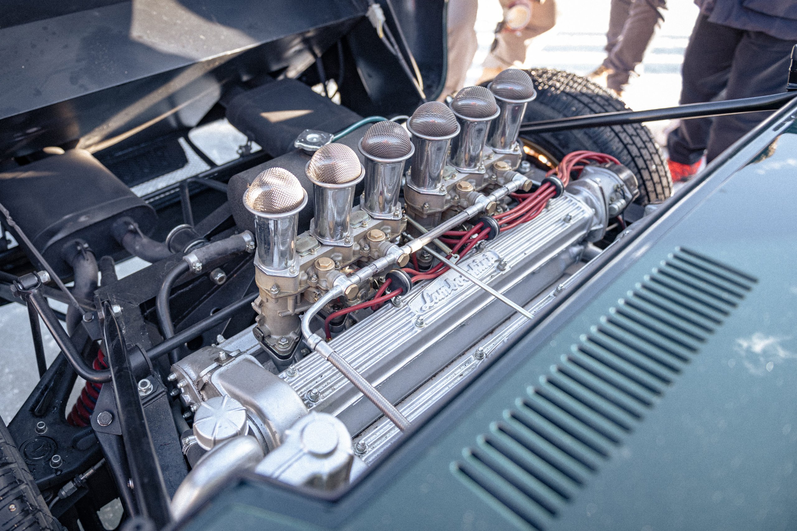 Close-up of the lamborghini miura p400s v12 engine bay showing six weber carburetors and lamborghini script on ribbed valve covers