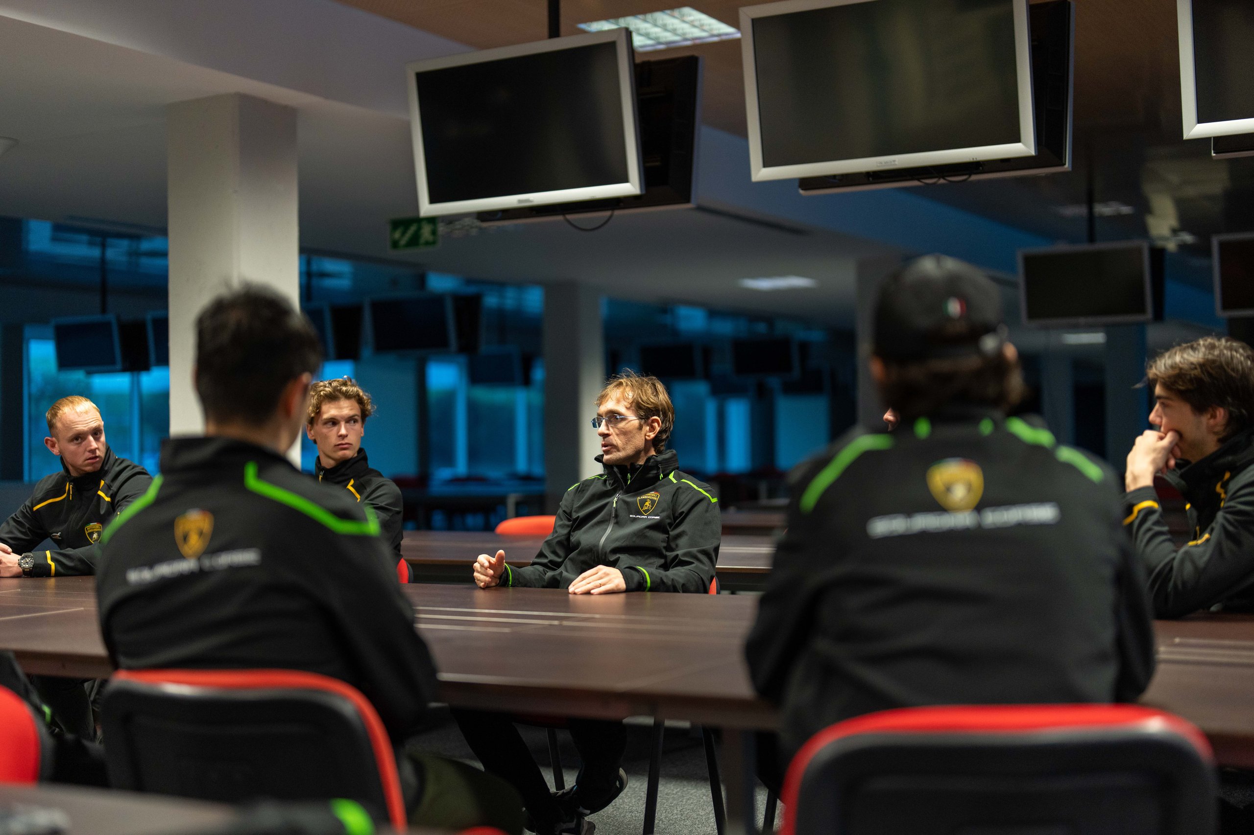 Lamborghini young driver program participants seated around a conference table during a briefing session at the portimão shootout