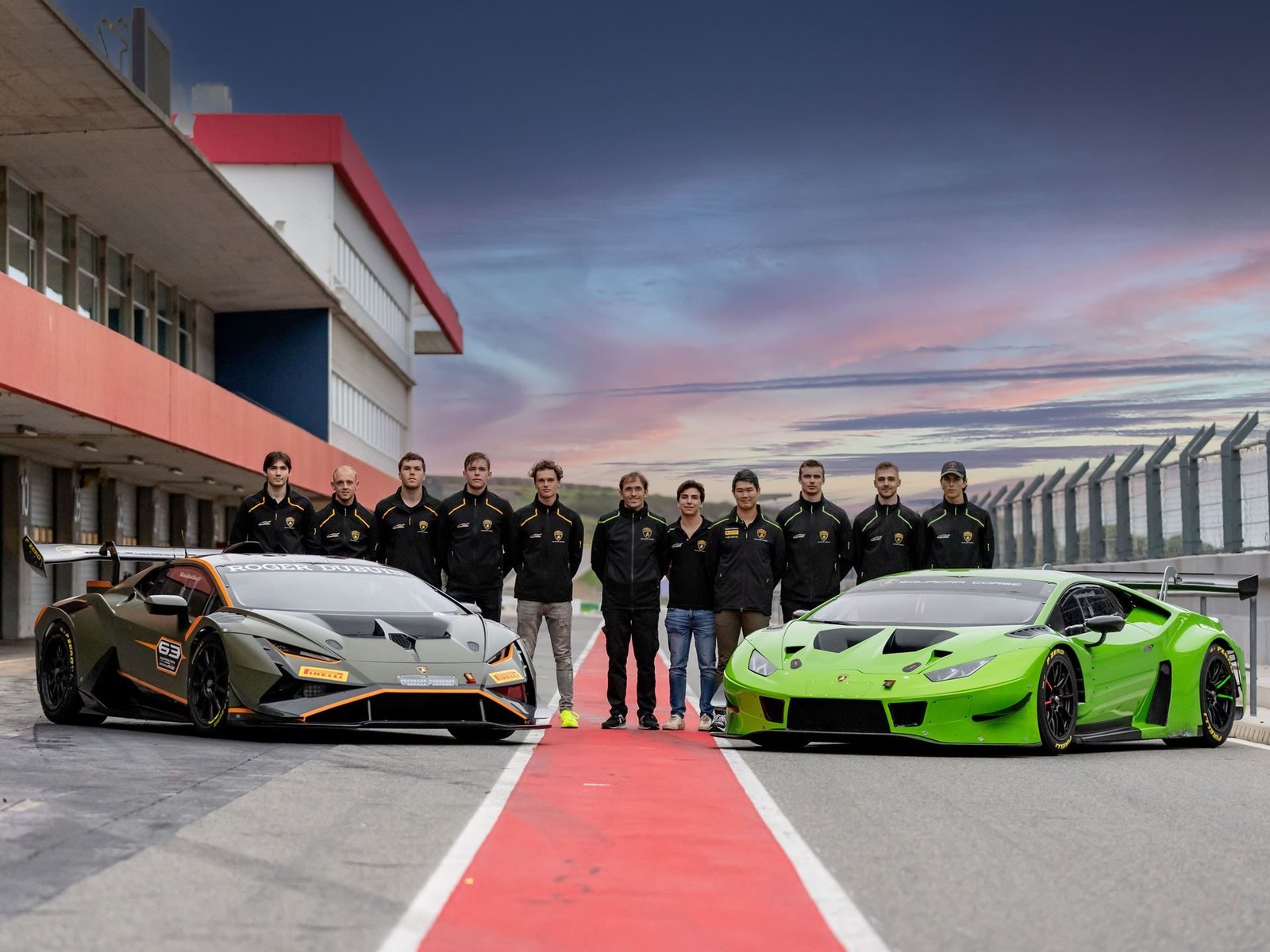 Lamborghini Squadra Corse young driver program winners standing between two Huracán GT3 EVO2 race cars at the Portimão circuit at sunset