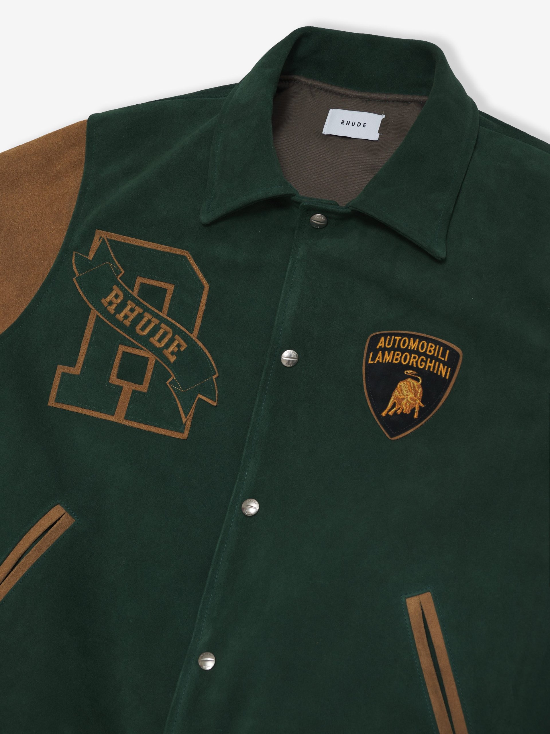 Rhude X Automobili Lamborghini: A Sterrato-Inspired Capsule That Reveals Where The Brand Is Headed 9 Flat lay of the dark green and brown varsity jacket from the rhude x automobili lamborghini collection, featuring the lamborghini shield and rhude emblem
