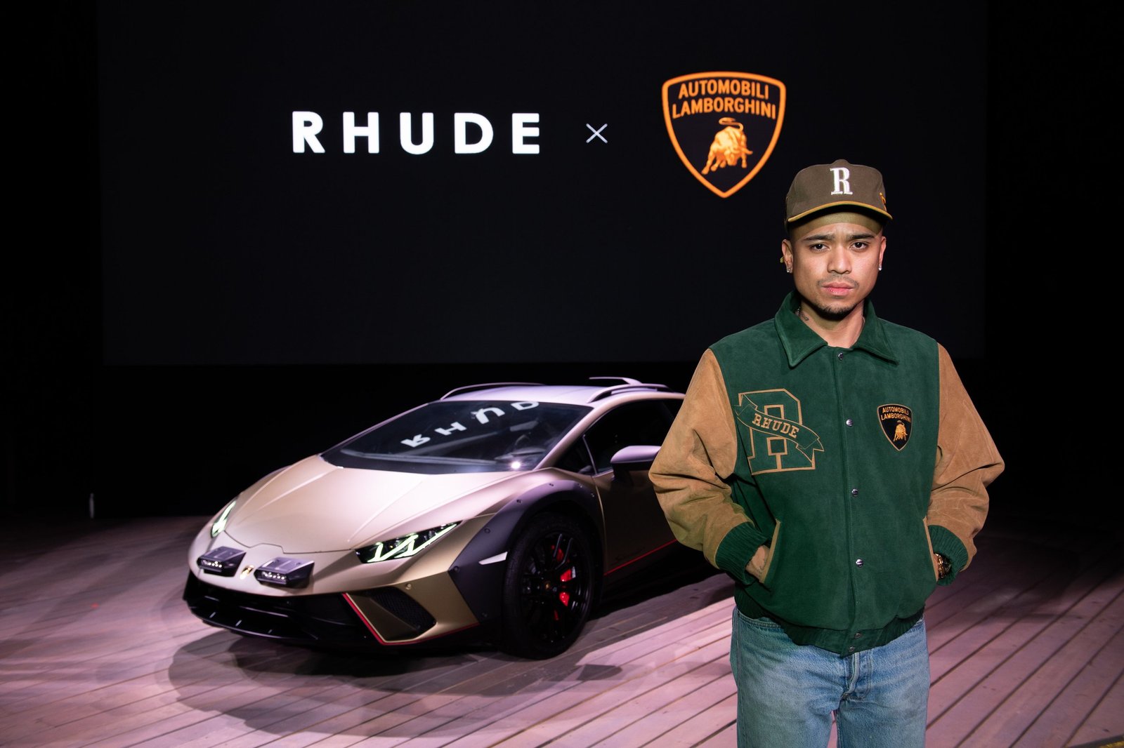 Rhuigi Villaseñor stands before a gold Lamborghini Huracán Sterrato at the Rhude x Automobili Lamborghini launch event during Art Basel Miami