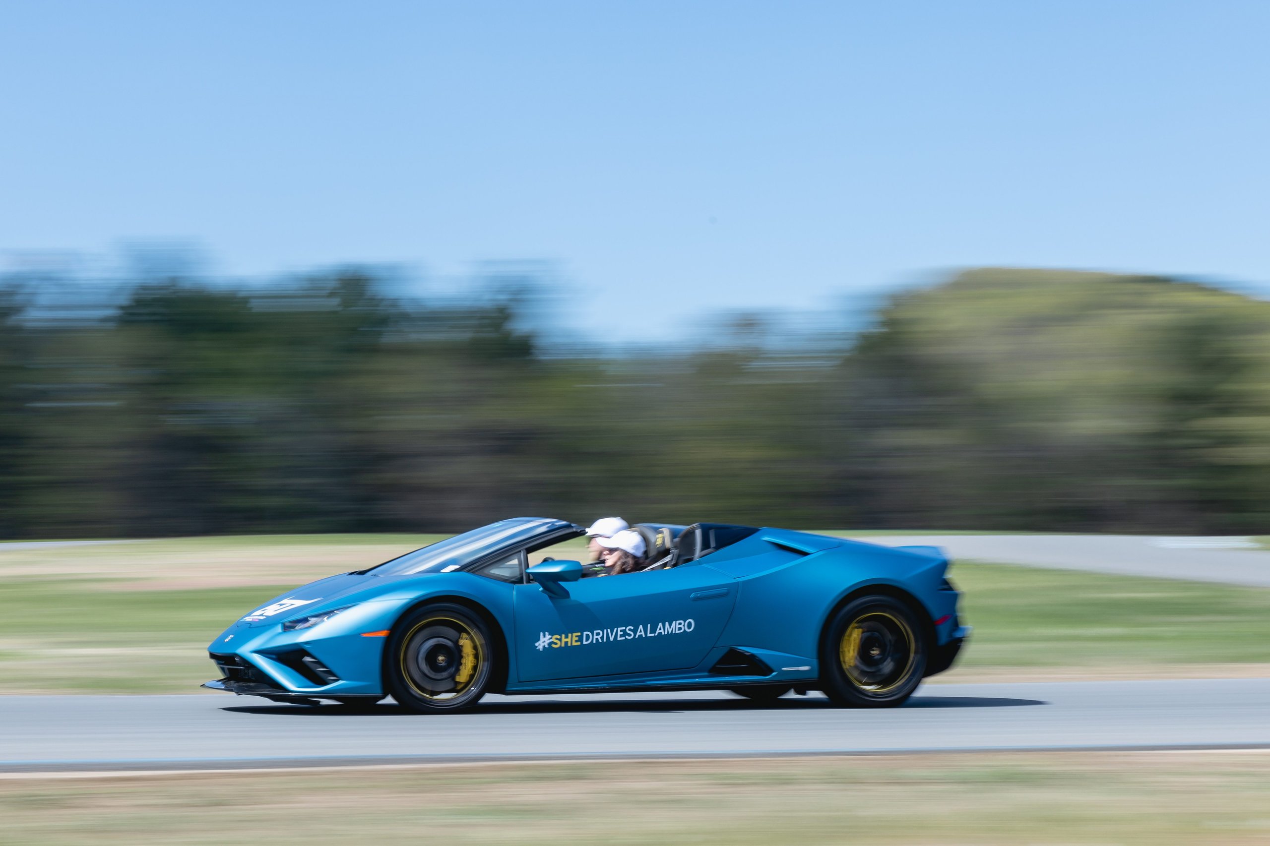 Shedrivesalambo: How Lamborghini Built A Supercar Community No Rival Bothered To Create 9 A blue lamborghini huracán evo spyder with shedrivesalambo branding in motion on a race track