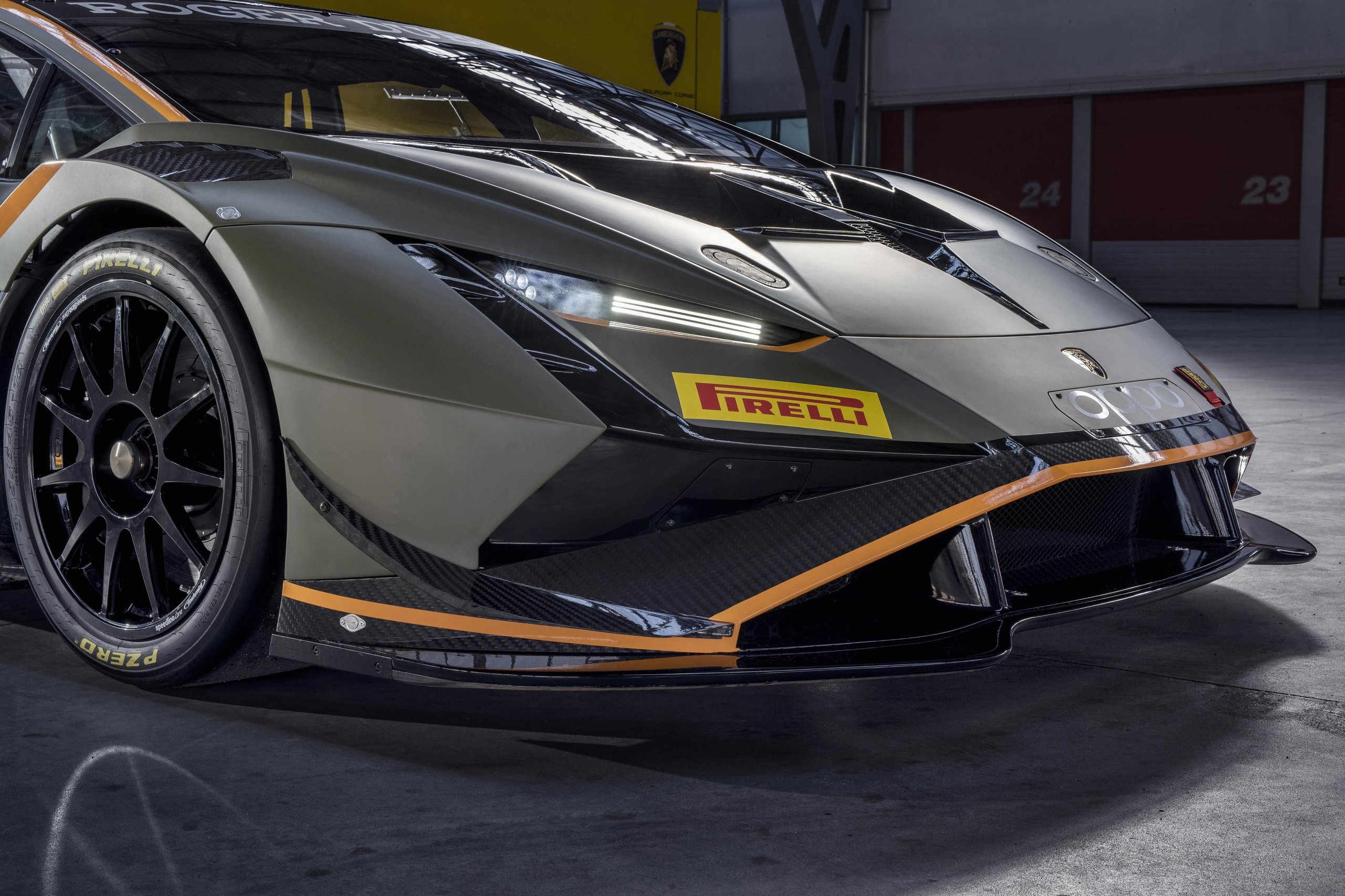 Close-up of the front left section of a lamborghini huracán super trofeo evo2 showing carbon fiber elements and pirelli branding in a pit garage