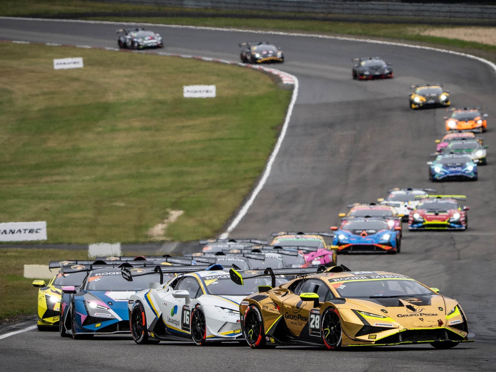 Super Trofeo Europe Joins The Fia Wec Bill At Imola, Placing Lamborghini'S Full Racing Ladder On One Stage 7 Group of lamborghini huracán super trofeo evo2 race cars navigating a turn, with a gold car leading white and blue competitors