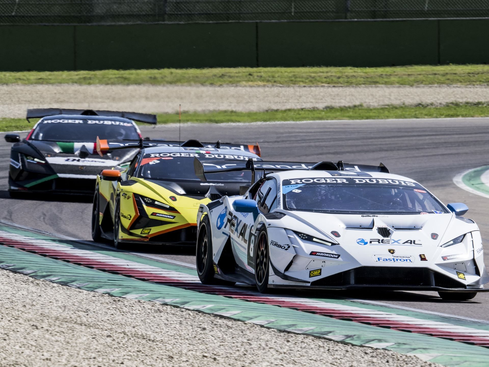 Super Trofeo Europe Joins The Fia Wec Bill At Imola, Placing Lamborghini'S Full Racing Ladder On One Stage 9 Three lamborghini huracán super trofeo evo2 race cars in a line cornering on a racetrack, with a white and blue car leading