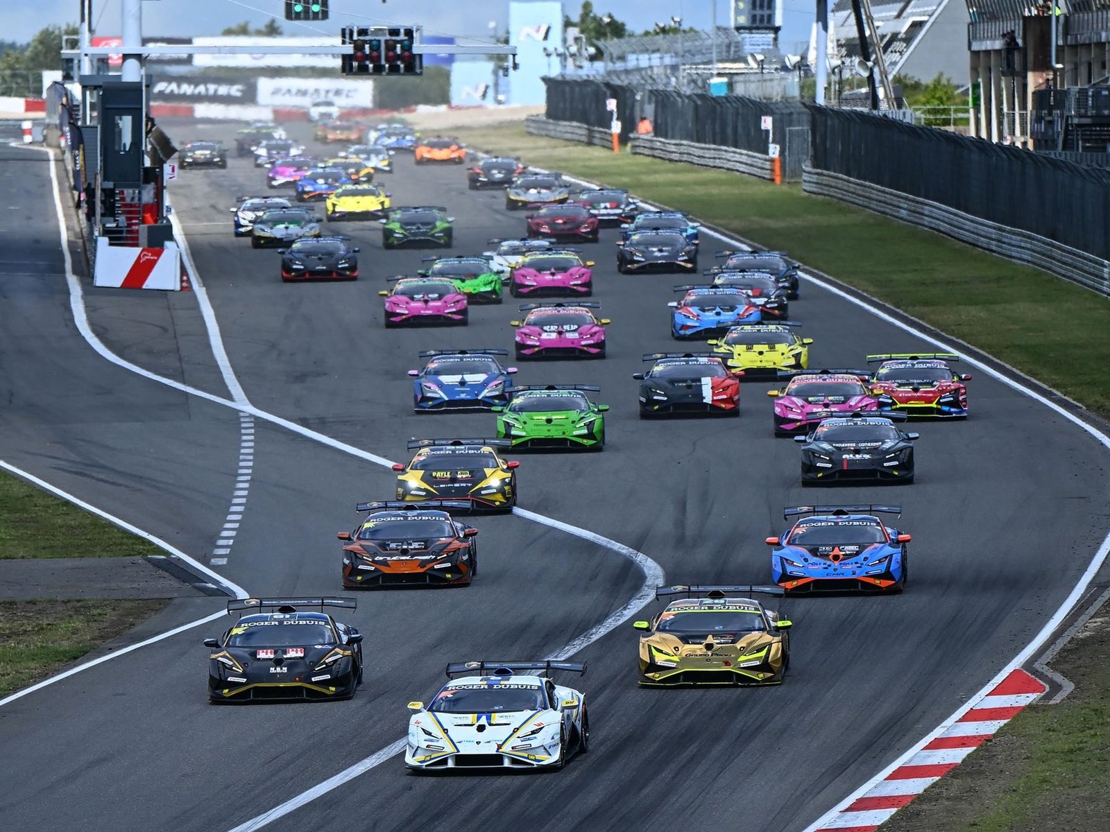 Full grid of Lamborghini Huracán Super Trofeo EVO2 race cars lined up at the start of a race, displaying a variety of vibrant racing liveries