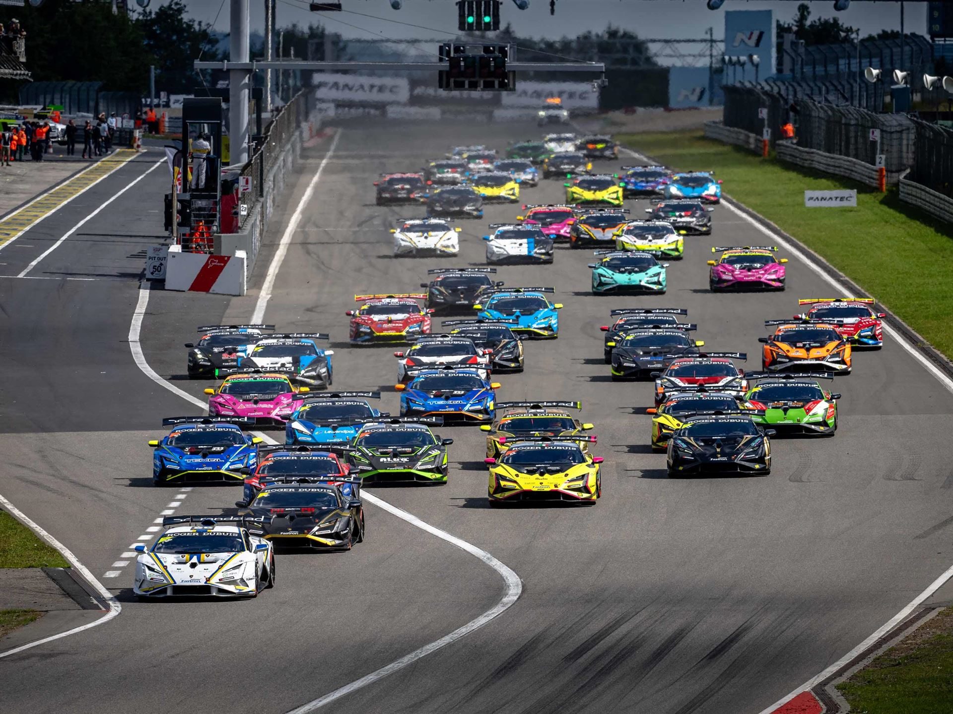 Split Weather, Split Winners: Bonduel And Orudzhev Trade Nürburgring Victories In Super Trofeo Europe 9 A large grid of lamborghini huracán super trofeo evo race cars in various liveries accelerating from the starting line on a clear day