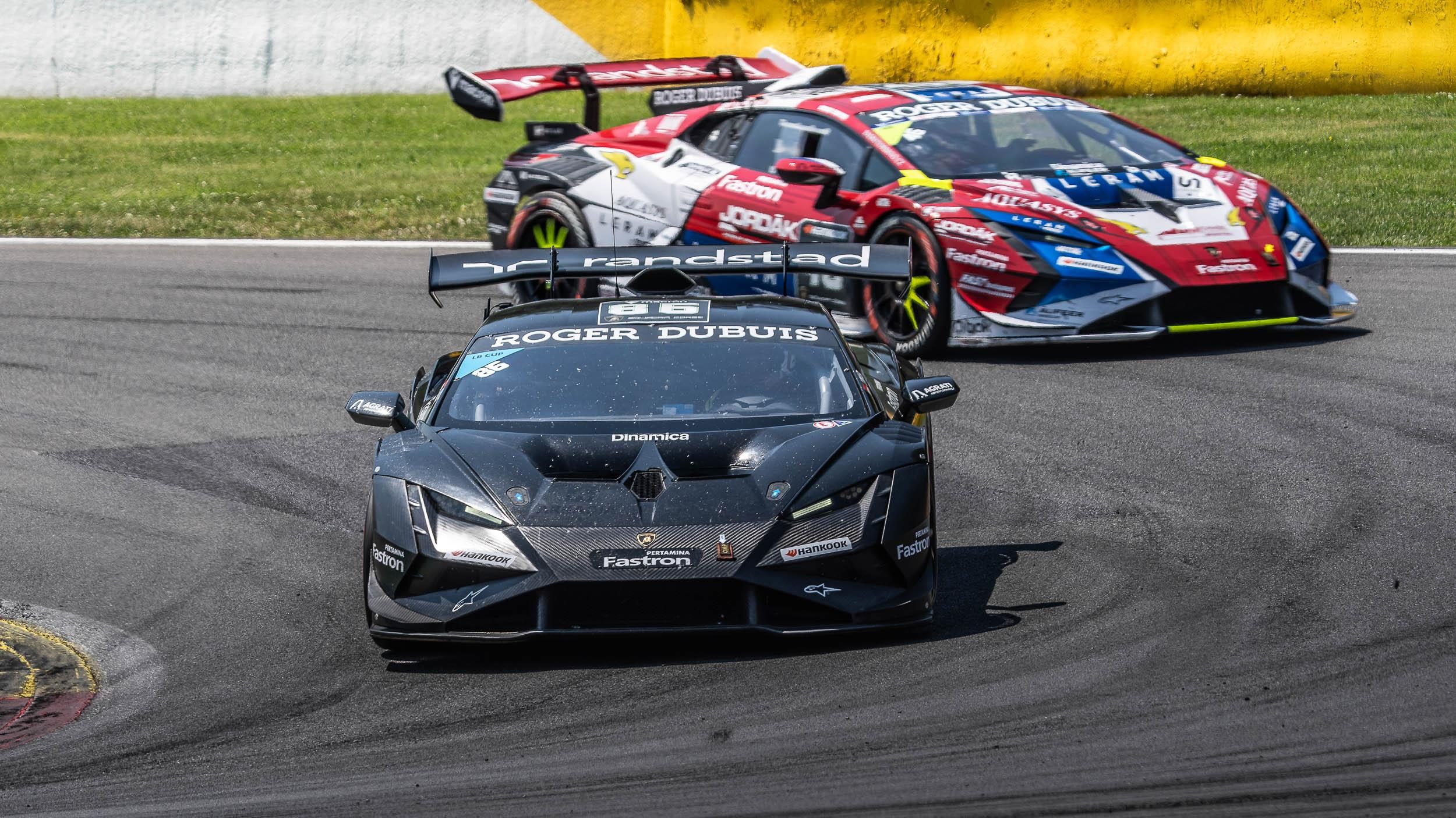A black lamborghini huracán super trofeo evo2 navigating a turn at spa-francorchamps with another car trailing behind