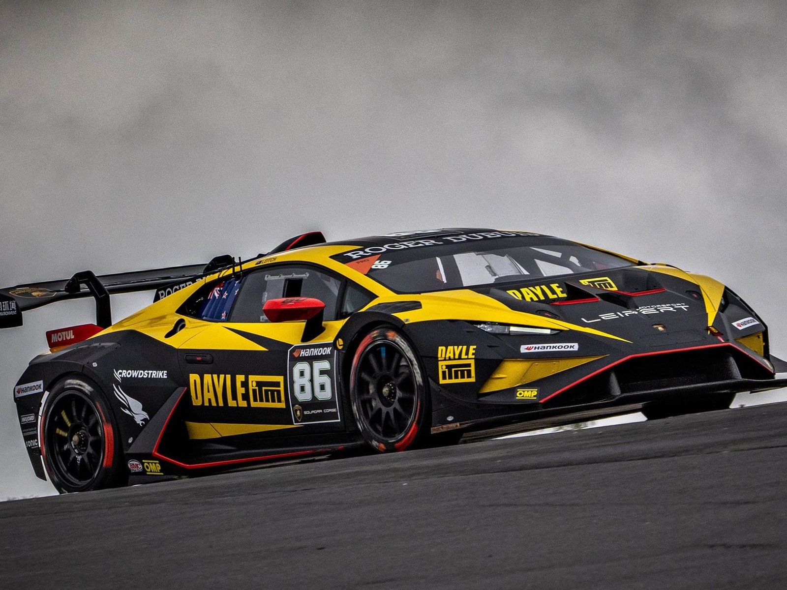 Yellow and black Lamborghini Huracán Super Trofeo EVO2 number 86 at speed on a race circuit under overcast skies