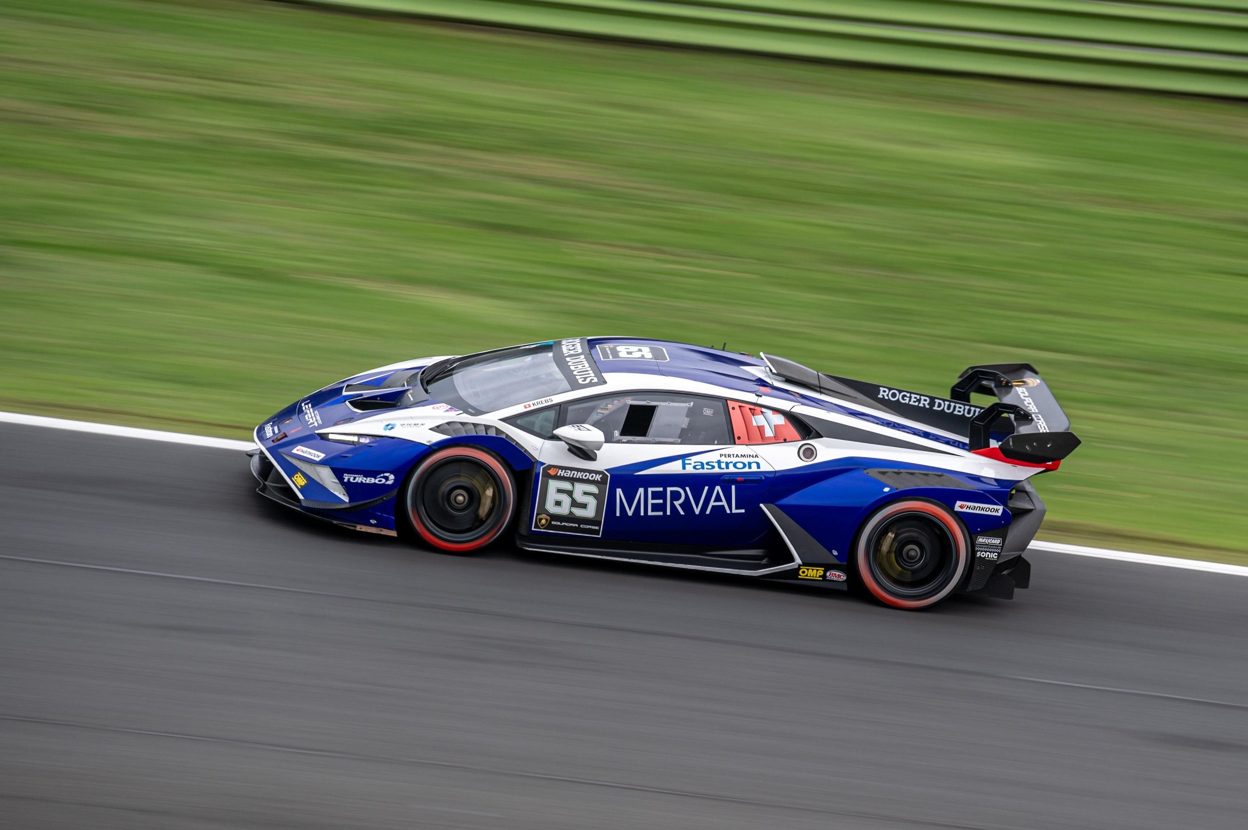 Fifty Cars, Four Open Championships, And One Week Left: Super Trofeo Europe'S Vallelunga Showdown 9 A blue and white lamborghini huracán super trofeo evo2 at speed on the vallelunga circuit with a blurred green background